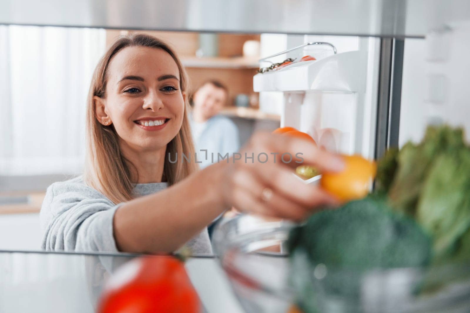 Using vegetables. Couple preparing food at home on the modern kitchen.