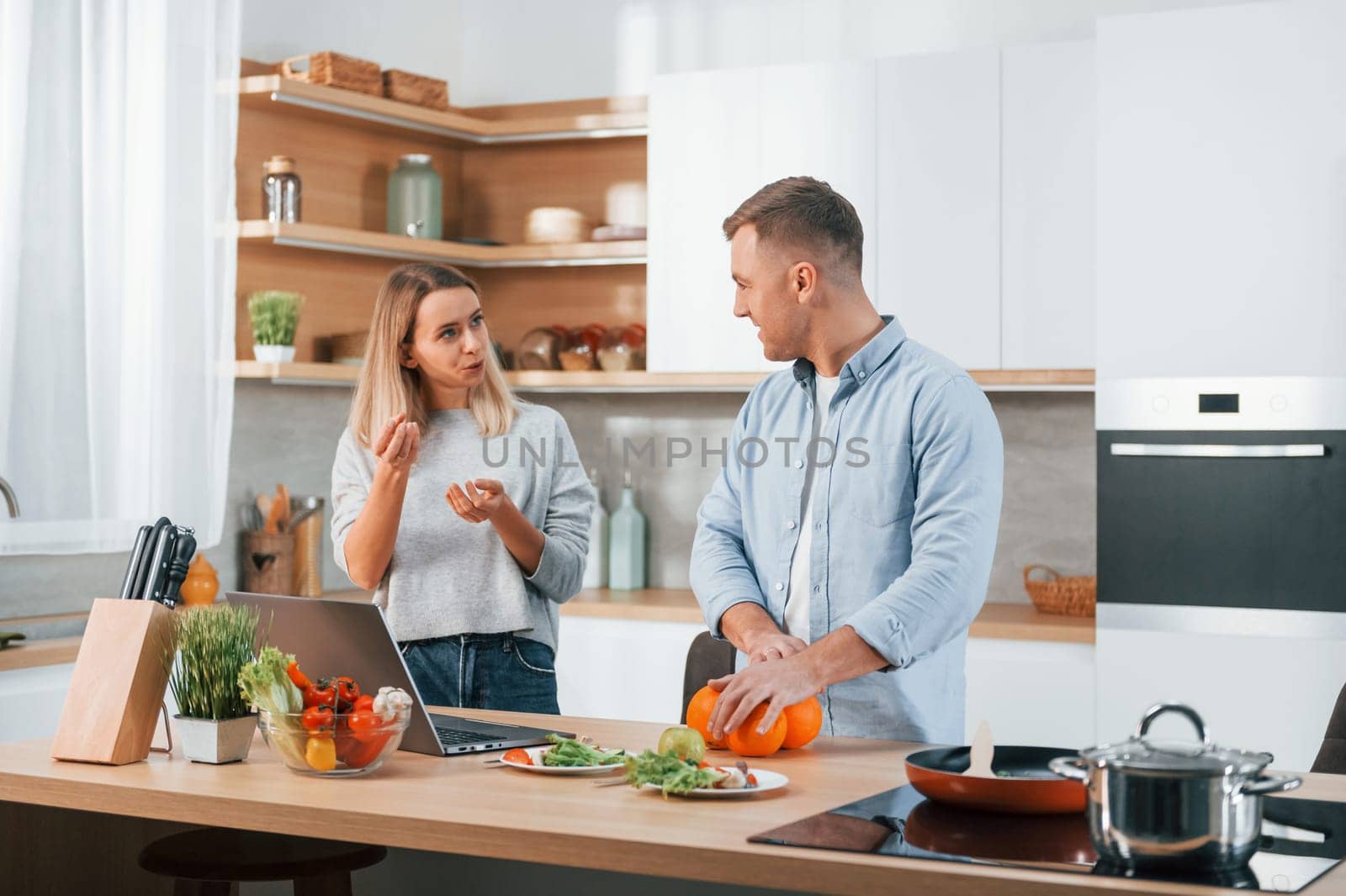 Having weekend together. Couple preparing food at home on the modern kitchen.