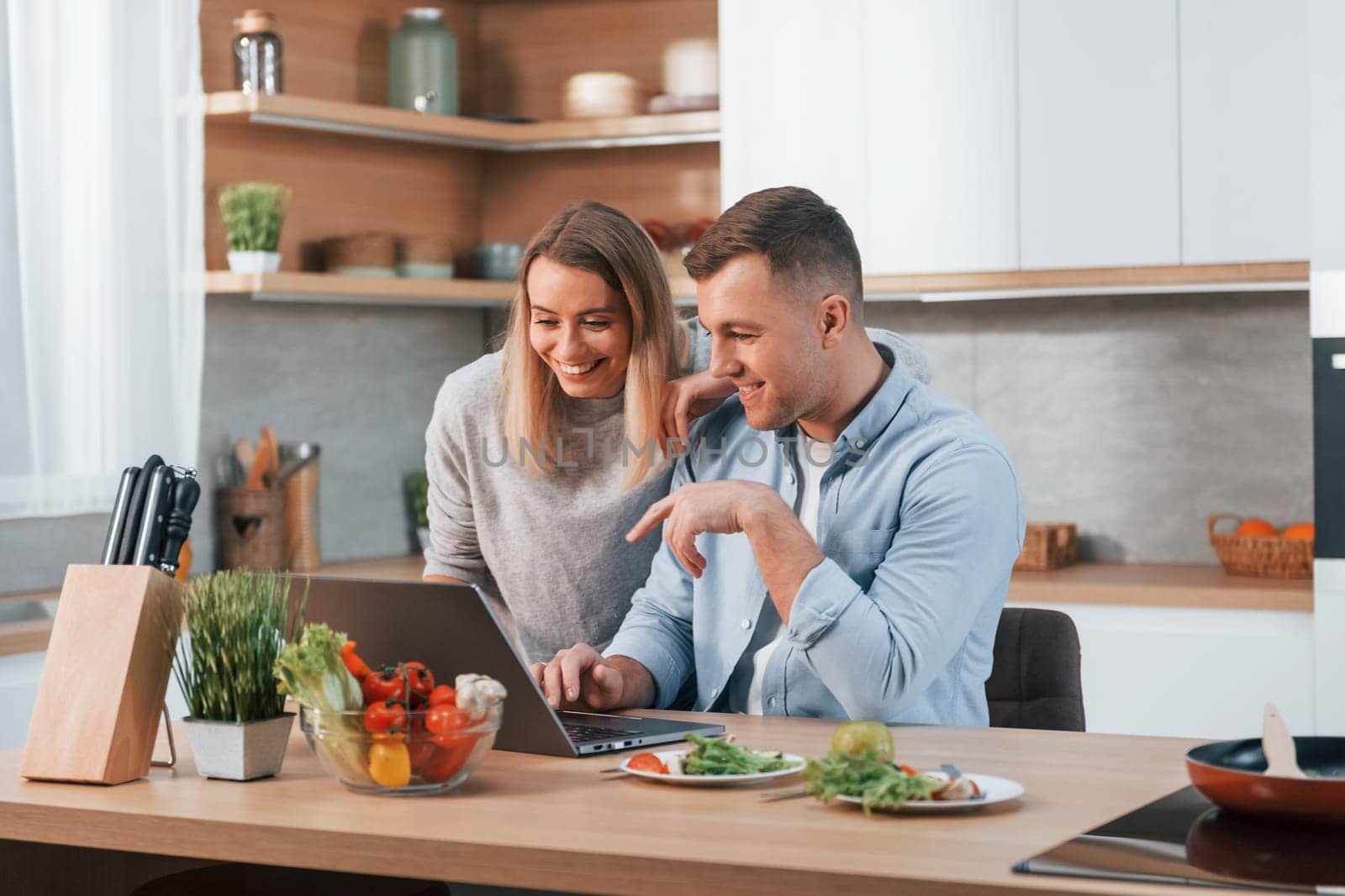 Having weekend together. Couple preparing food at home on the modern kitchen.