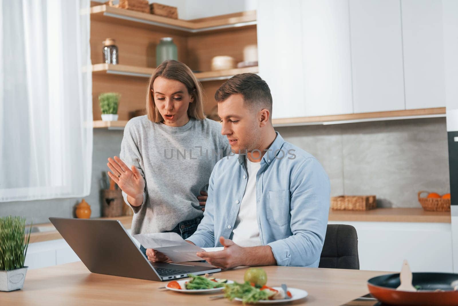 Using internet. Couple preparing food at home on the modern kitchen.