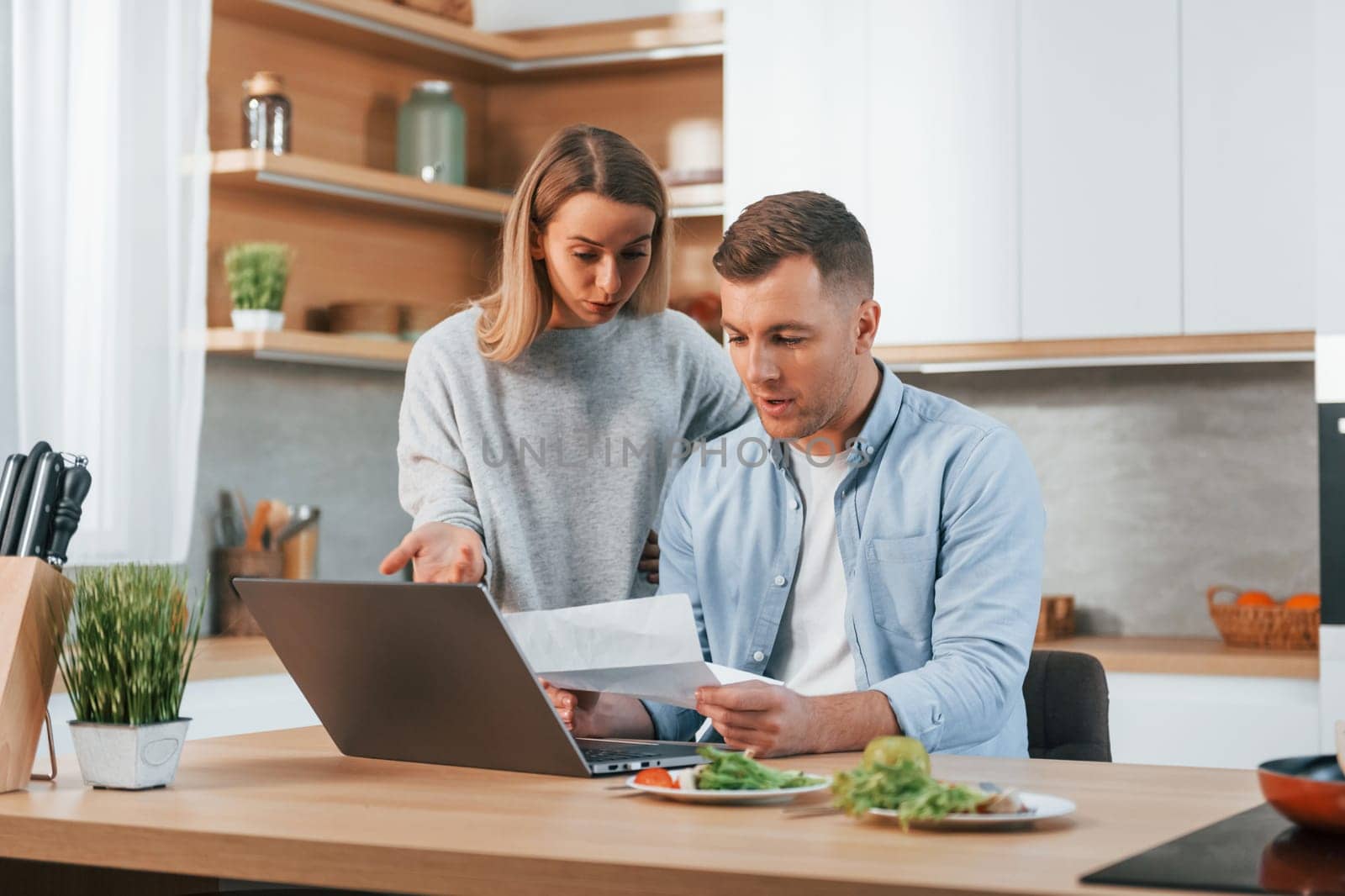 Using internet. Couple preparing food at home on the modern kitchen.