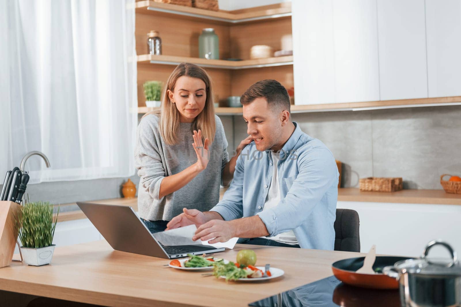 Using internet. Couple preparing food at home on the modern kitchen.