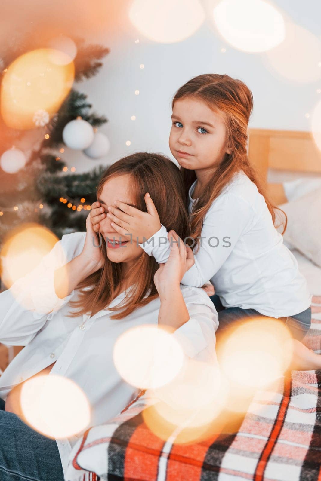 Having fun. Mother with her little daughter is having fun indoors on the bed.