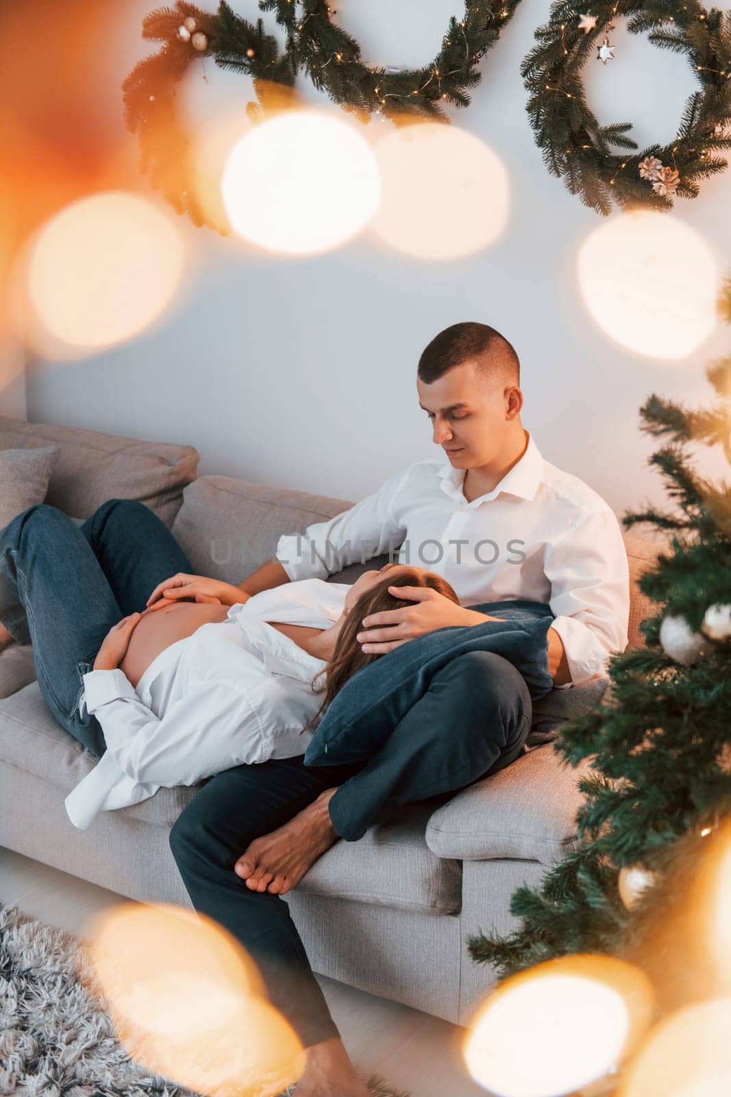 Woman is pregnant. Lovely couple celebrating holidays together indoors.