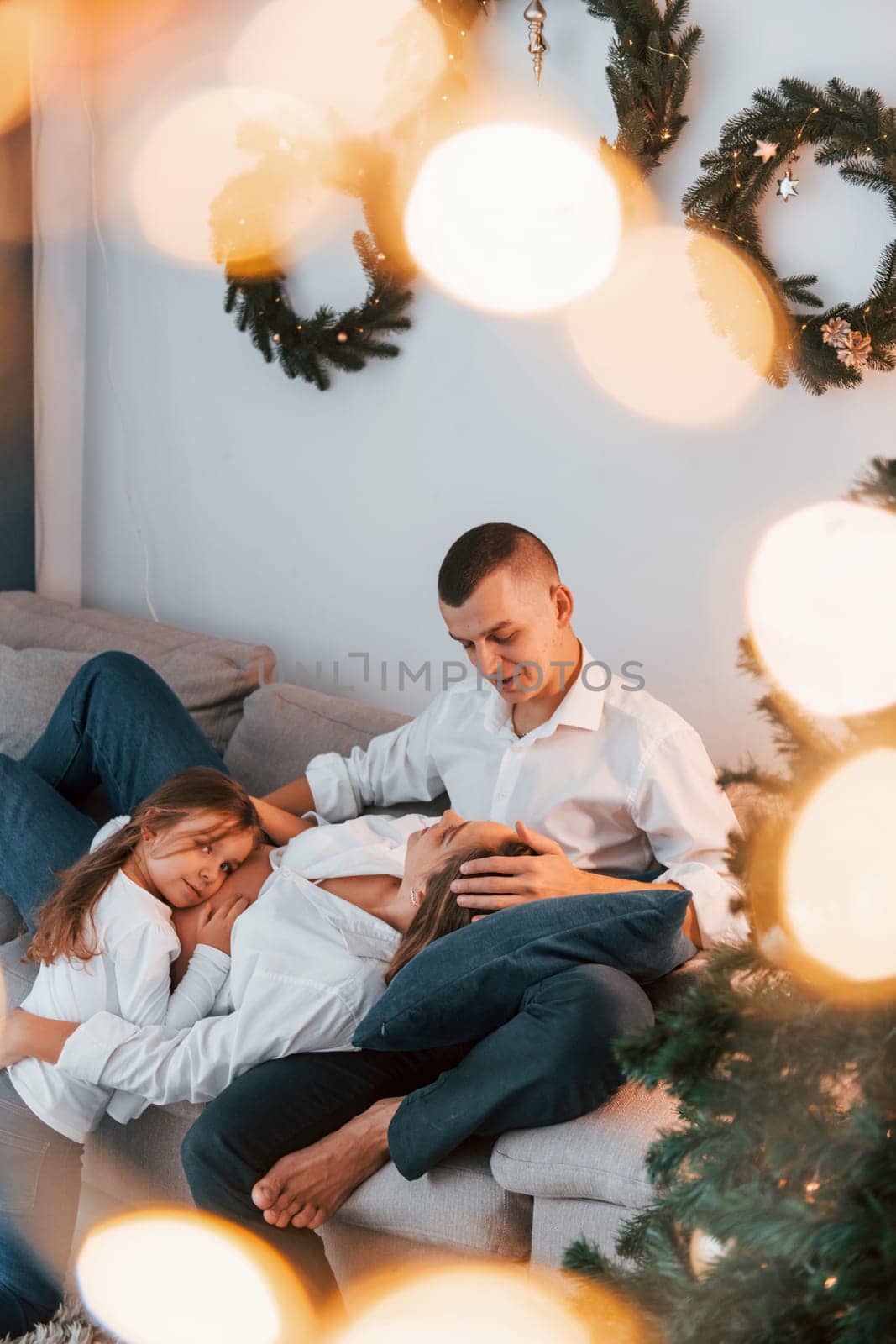 Laying down on the bed. Happy family celebrating holidays indoors together.