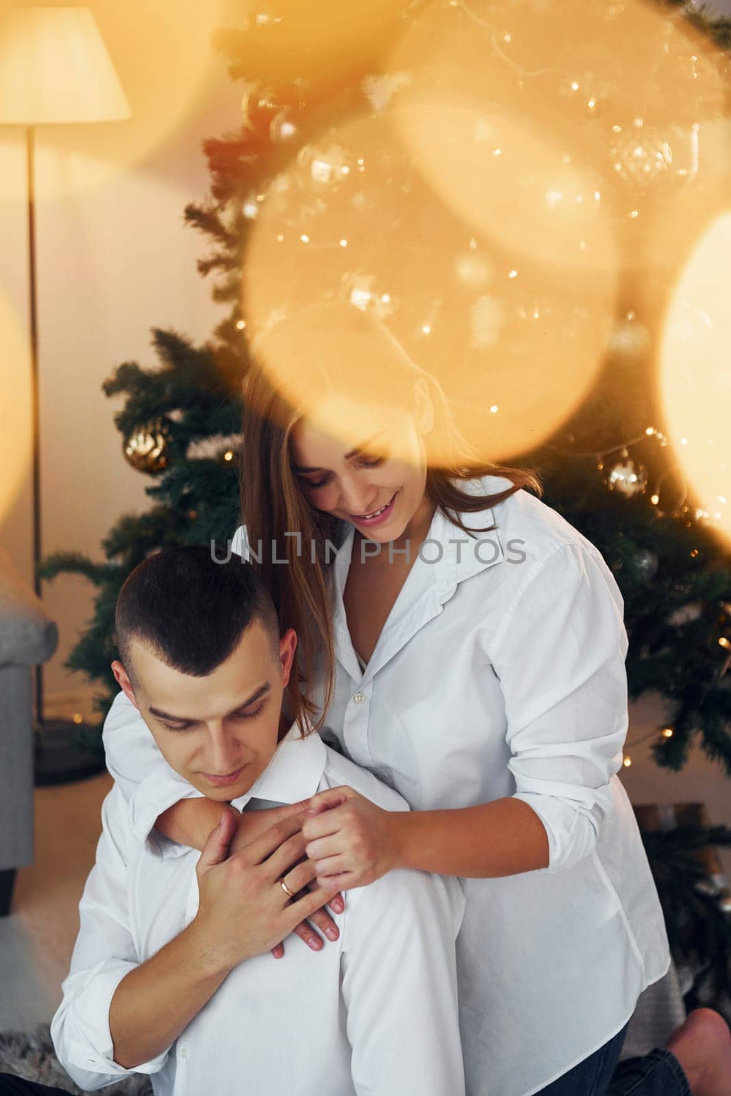 Embracing each other. Lovely couple celebrating holidays together indoors.