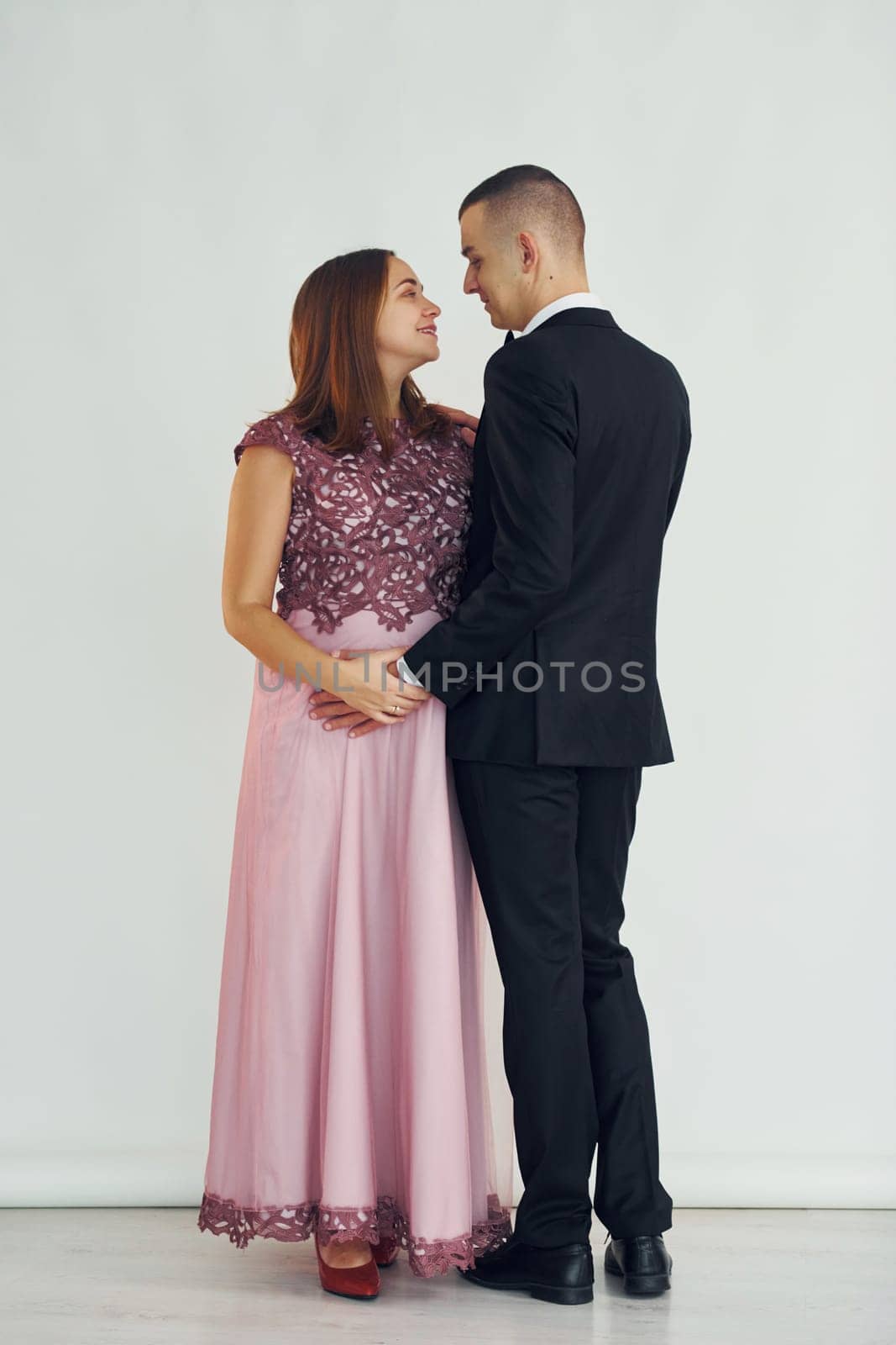 Couple in formal clothes standing in the studio with white background.