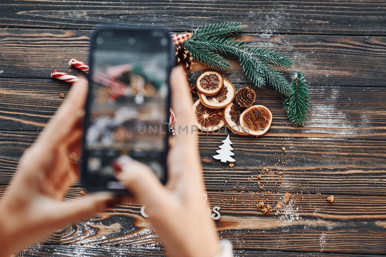 Woman holding phone. Christmas background with holiday decoration.