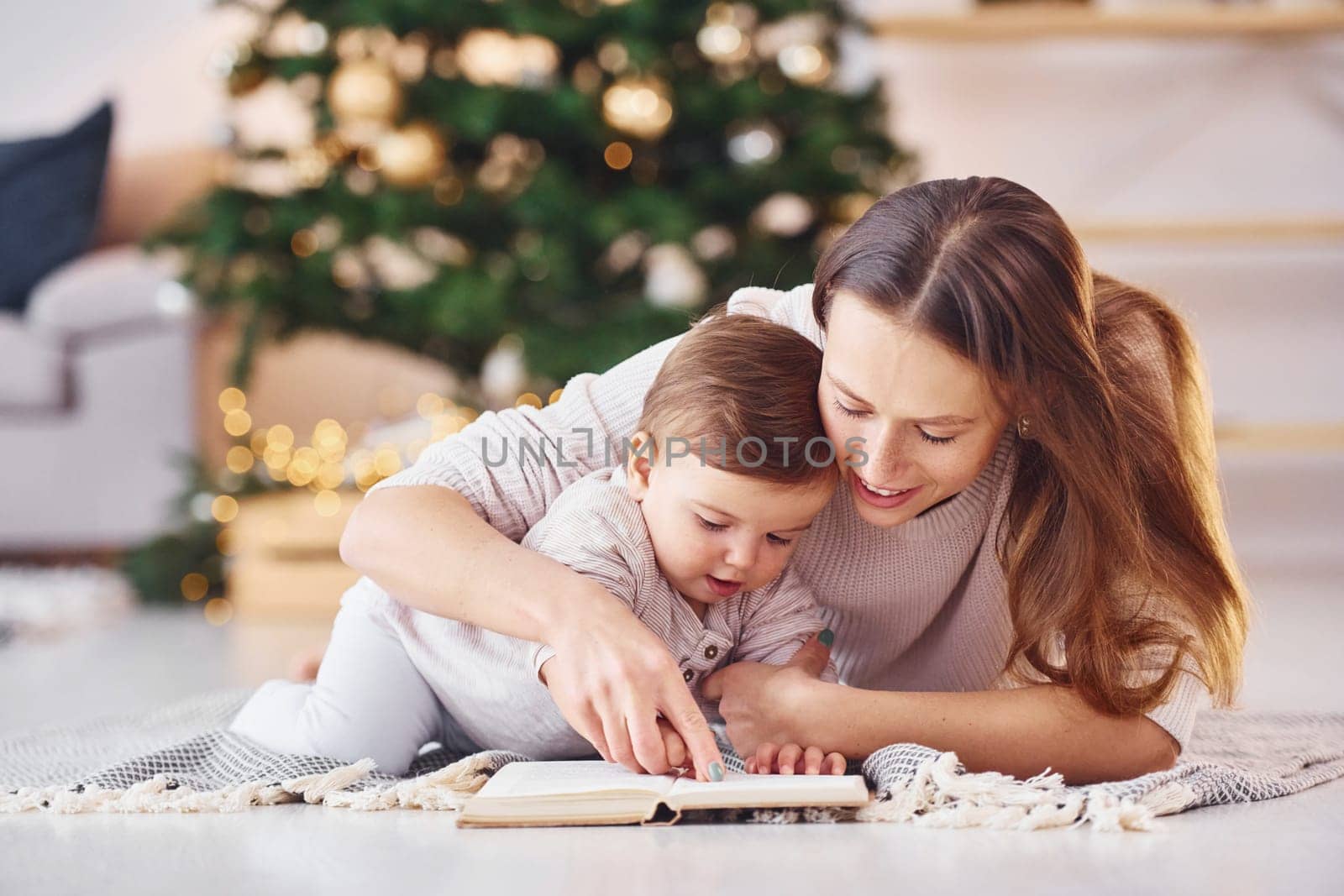 Reading book together. Mother with her little daughter is indoors at home together.