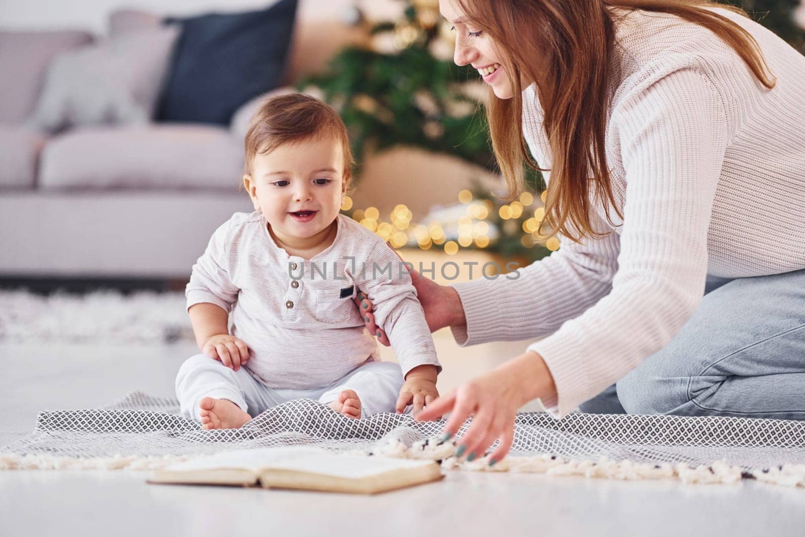 Reading book together. Mother with her little daughter is indoors at home together.