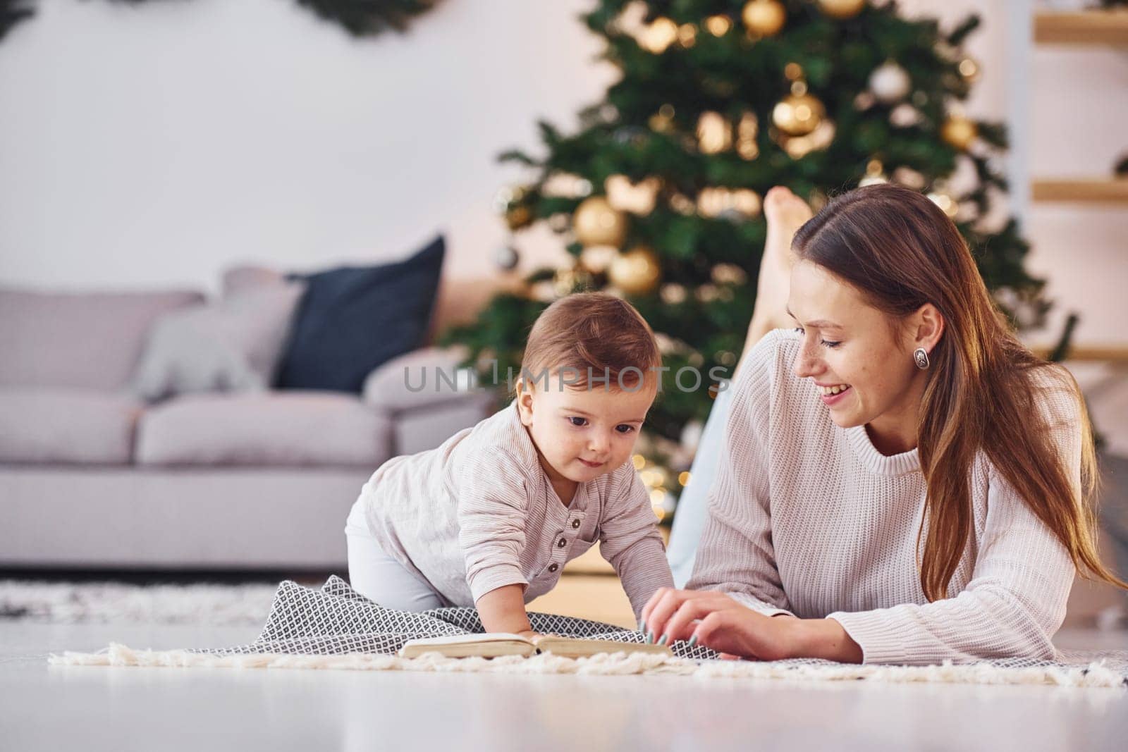 Reading book together. Mother with her little daughter is indoors at home together.