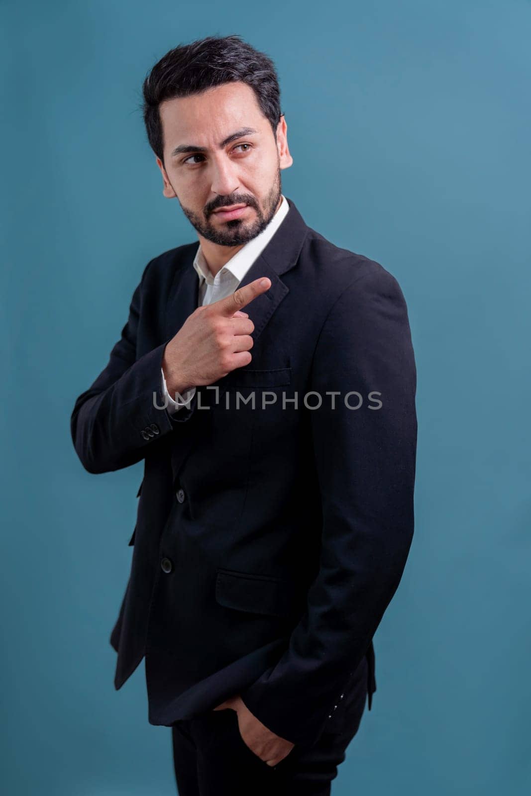 Confident businessman in formal suit pointing finger up to indicate promotion or advertising with excited and amazed facial expression and gesture on isolated background. Fervent