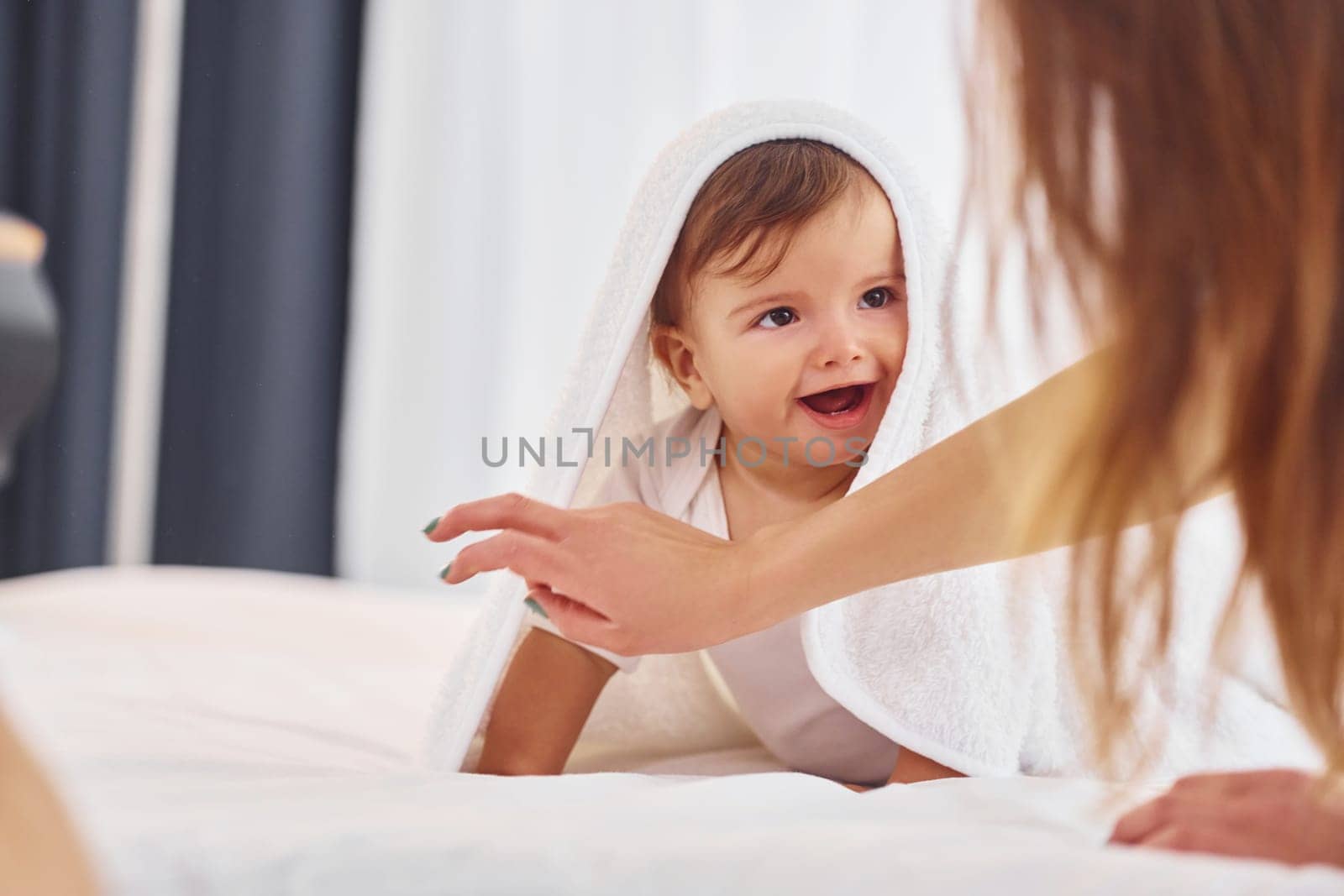 Laying down on the bed. Mother with her little daughter is indoors at home together.