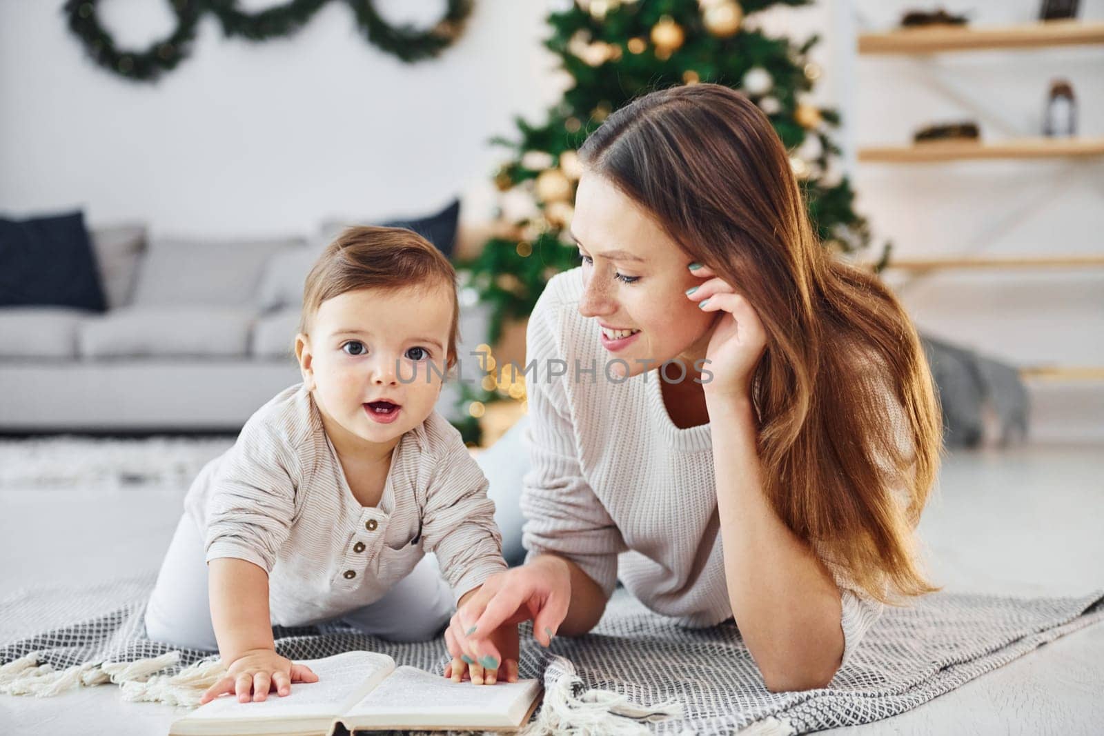 Sitting on the ground. Mother with her little daughter is indoors at home together.