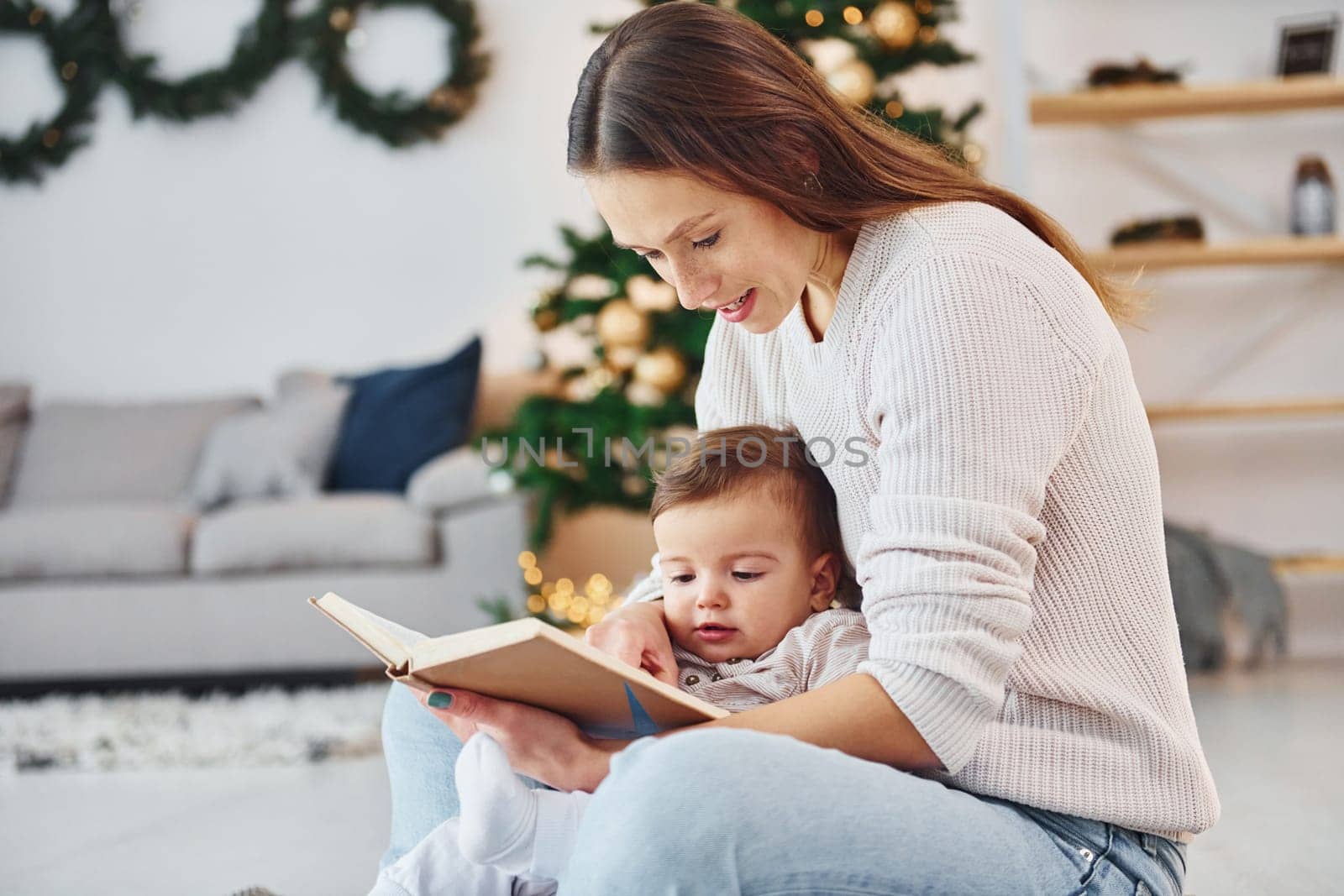 Sitting on the ground. Mother with her little daughter is indoors at home together.