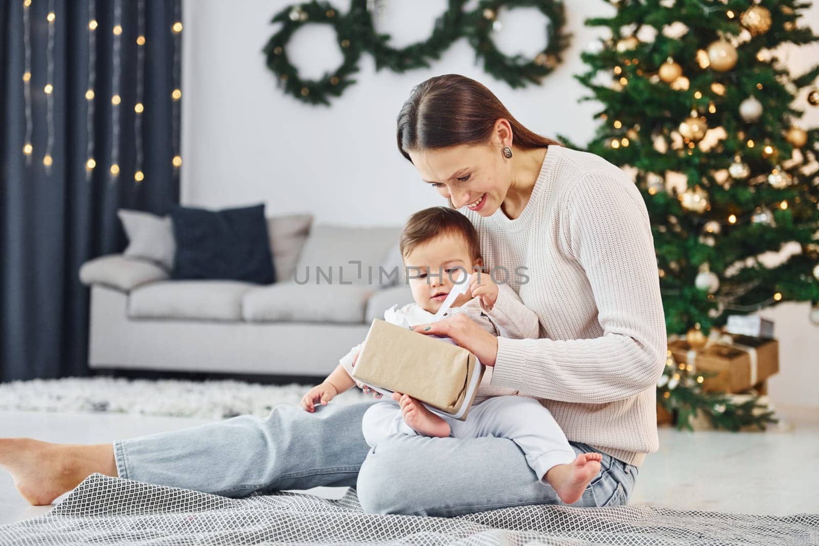 Sitting on the ground. Mother with her little daughter is indoors at home together.