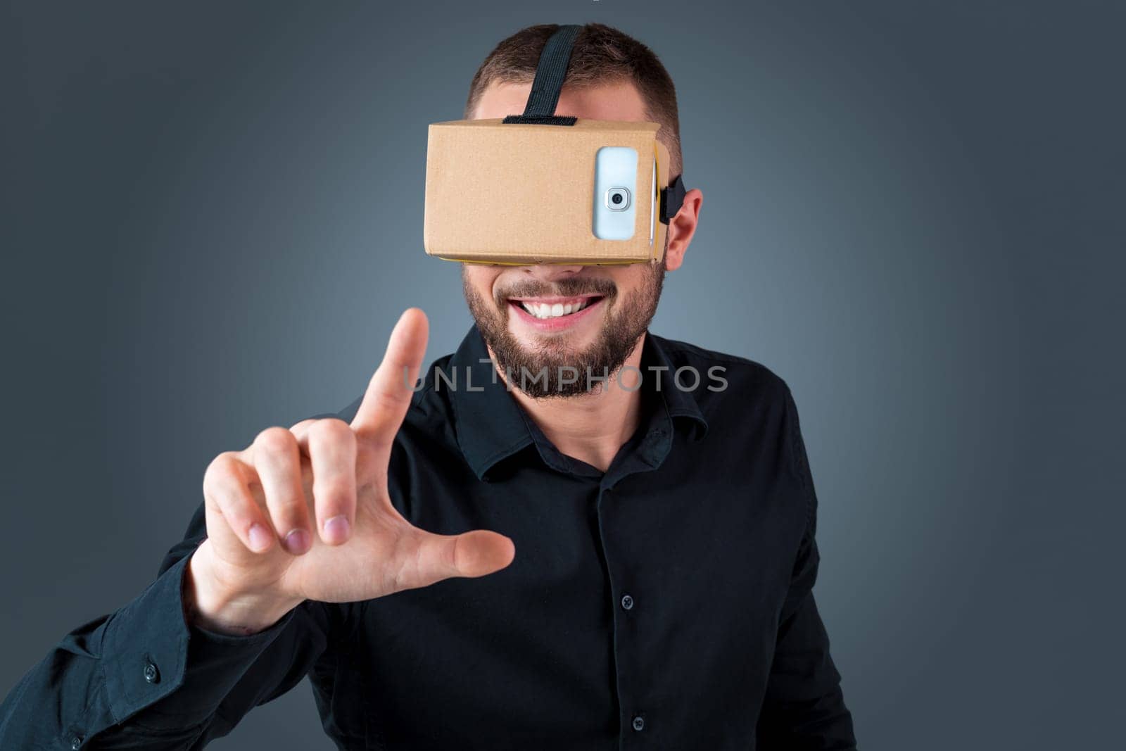 Excited young man using a VR headset glasses and experiencing virtual reality on grey blue background
