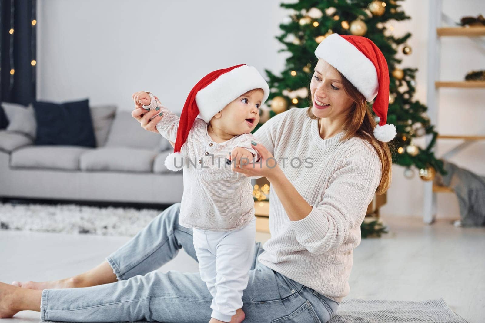 Celebrating Christmas. Mother with her little daughter is indoors at home together.