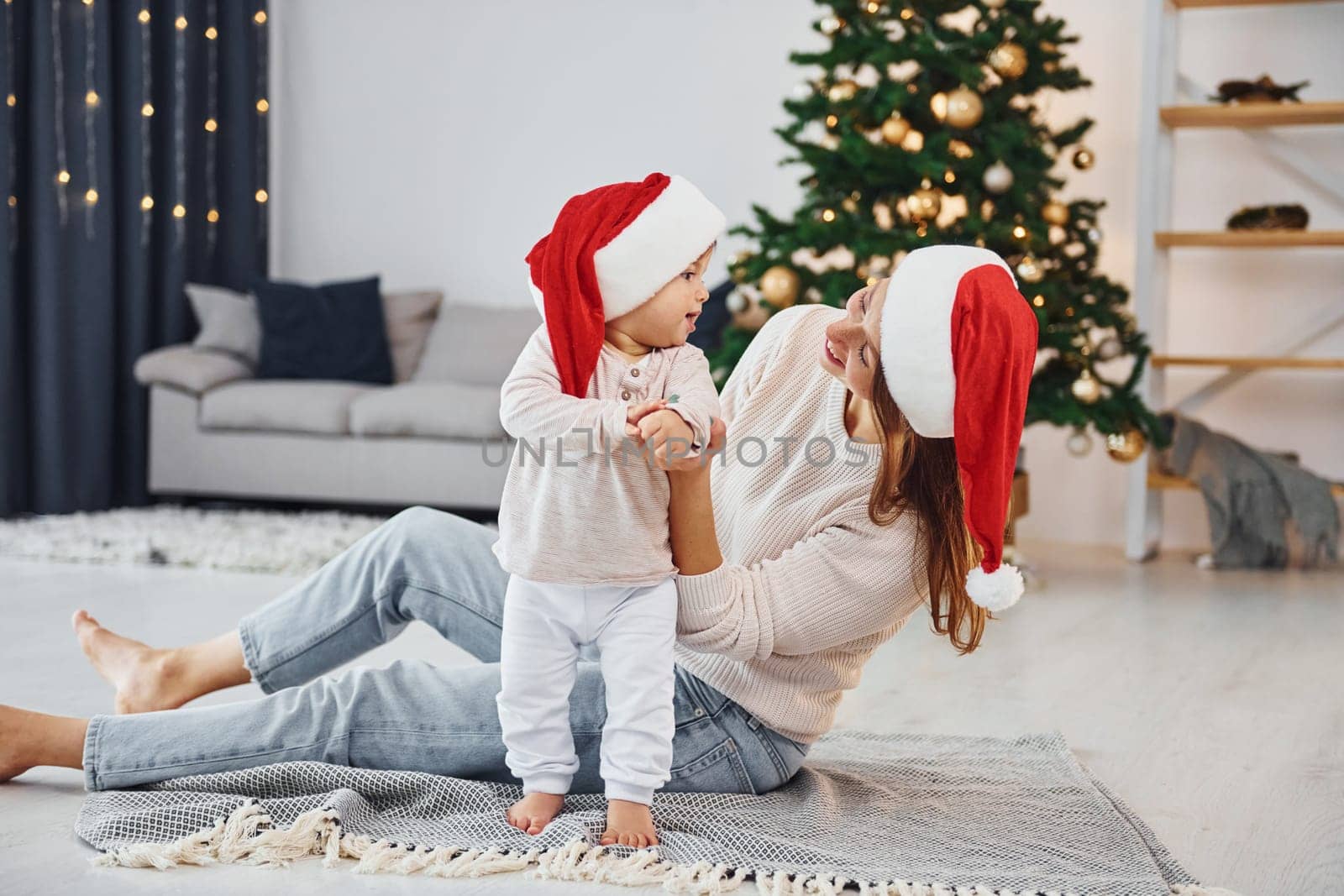 Celebrating Christmas. Mother with her little daughter is indoors at home together.
