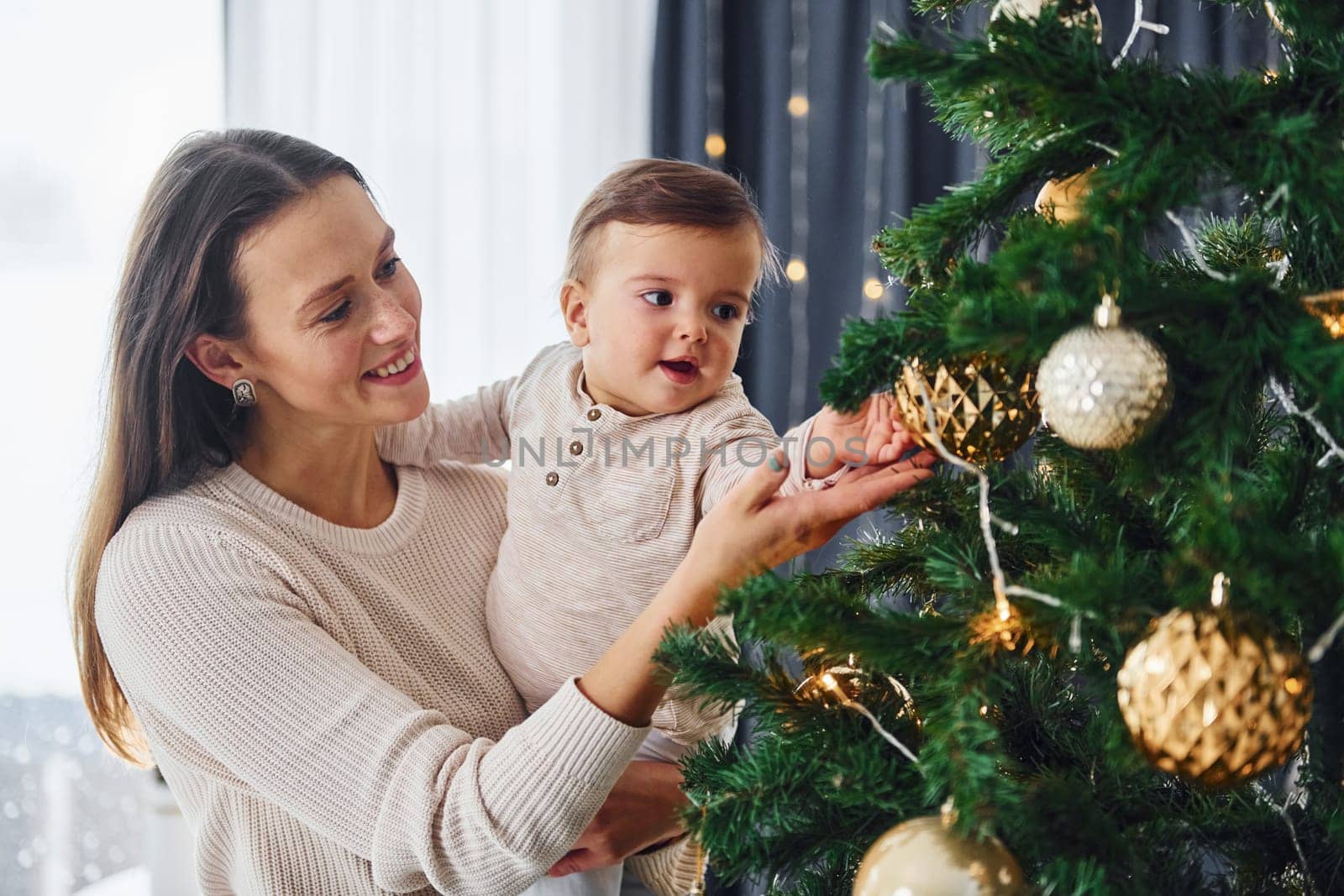 Mother with her little daughter is indoors at home together.