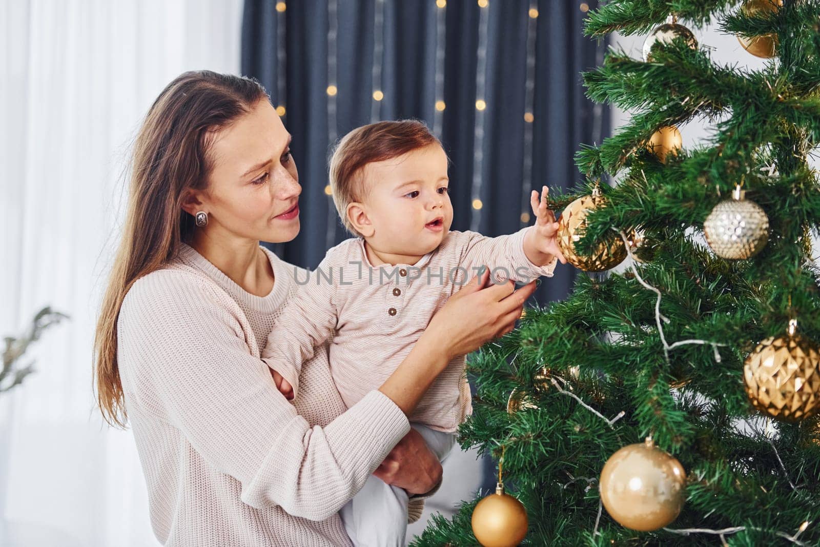 Mother with her little daughter is indoors at home together.