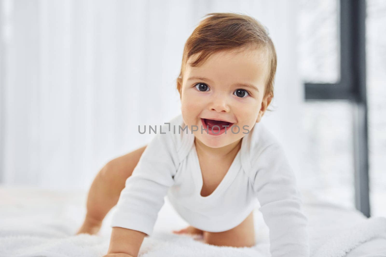 Playing on the bed. Cute little baby is indoors in the domestic room.