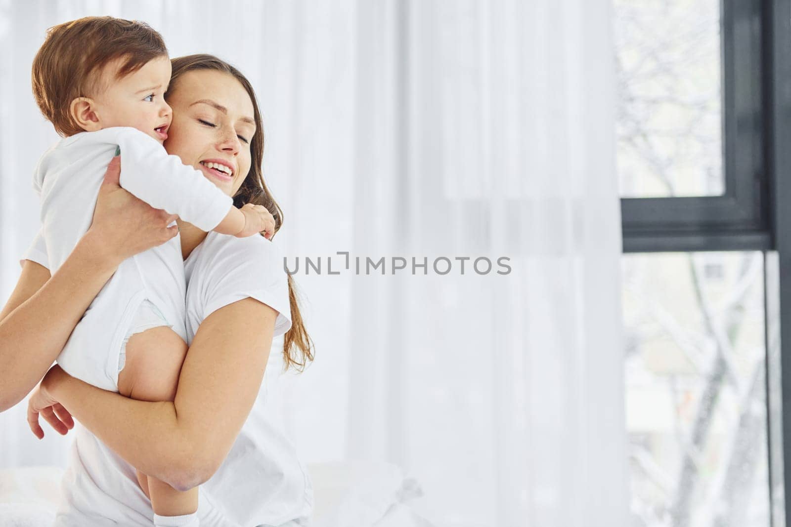 Embracing each other. Mother with her little daughter is indoors at home together.