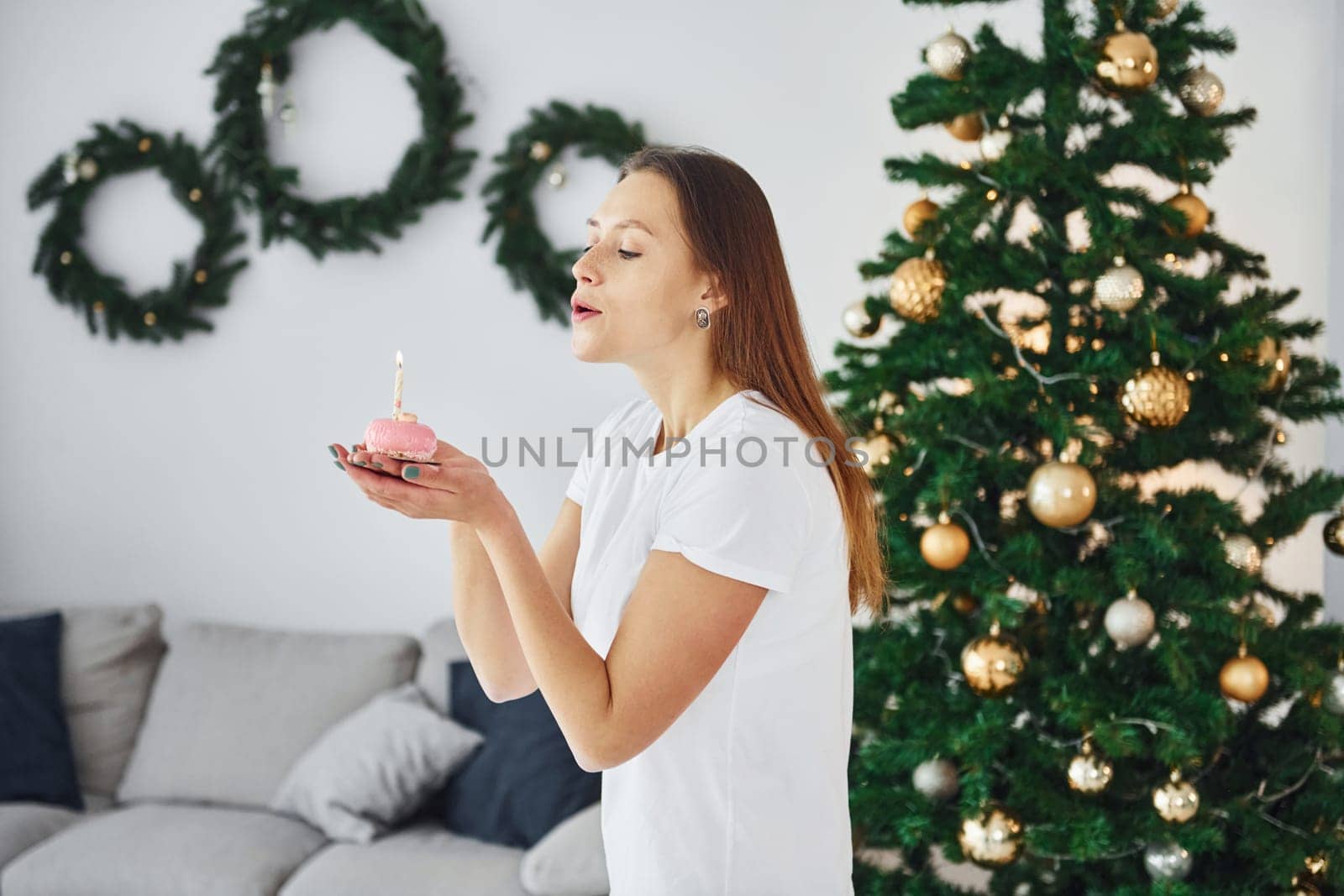 Christmas mood. Young woman in casual clothes is indoors in domestic room.