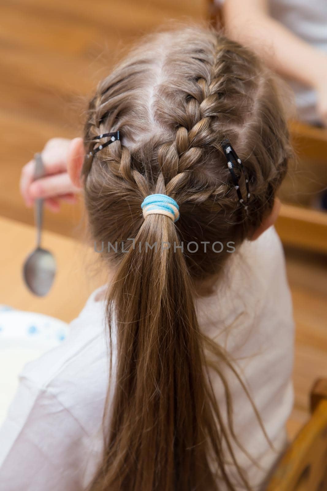 Close-up of a hairstyle with pigtails on the girl's head and a ponytail of hair. Hair styling is done with hairpins and an elastic band. Only the back of the head with a haircut.