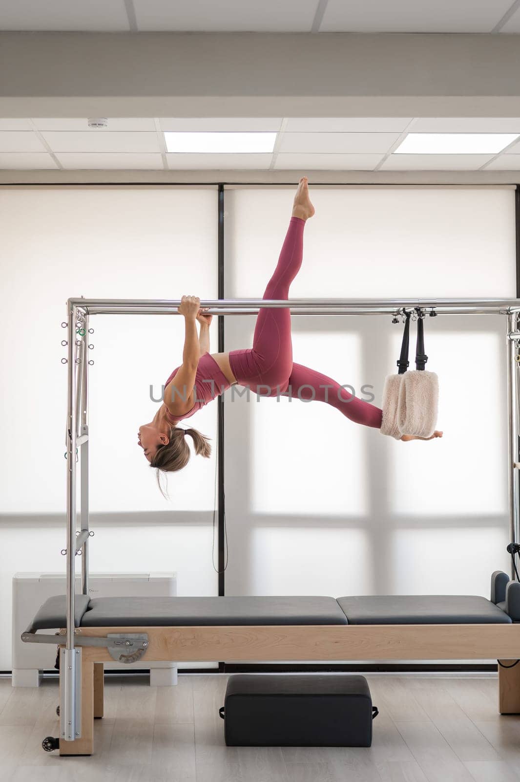 Beautiful asian woman in pink sportswear doing pilates on bed reformer. by mrwed54