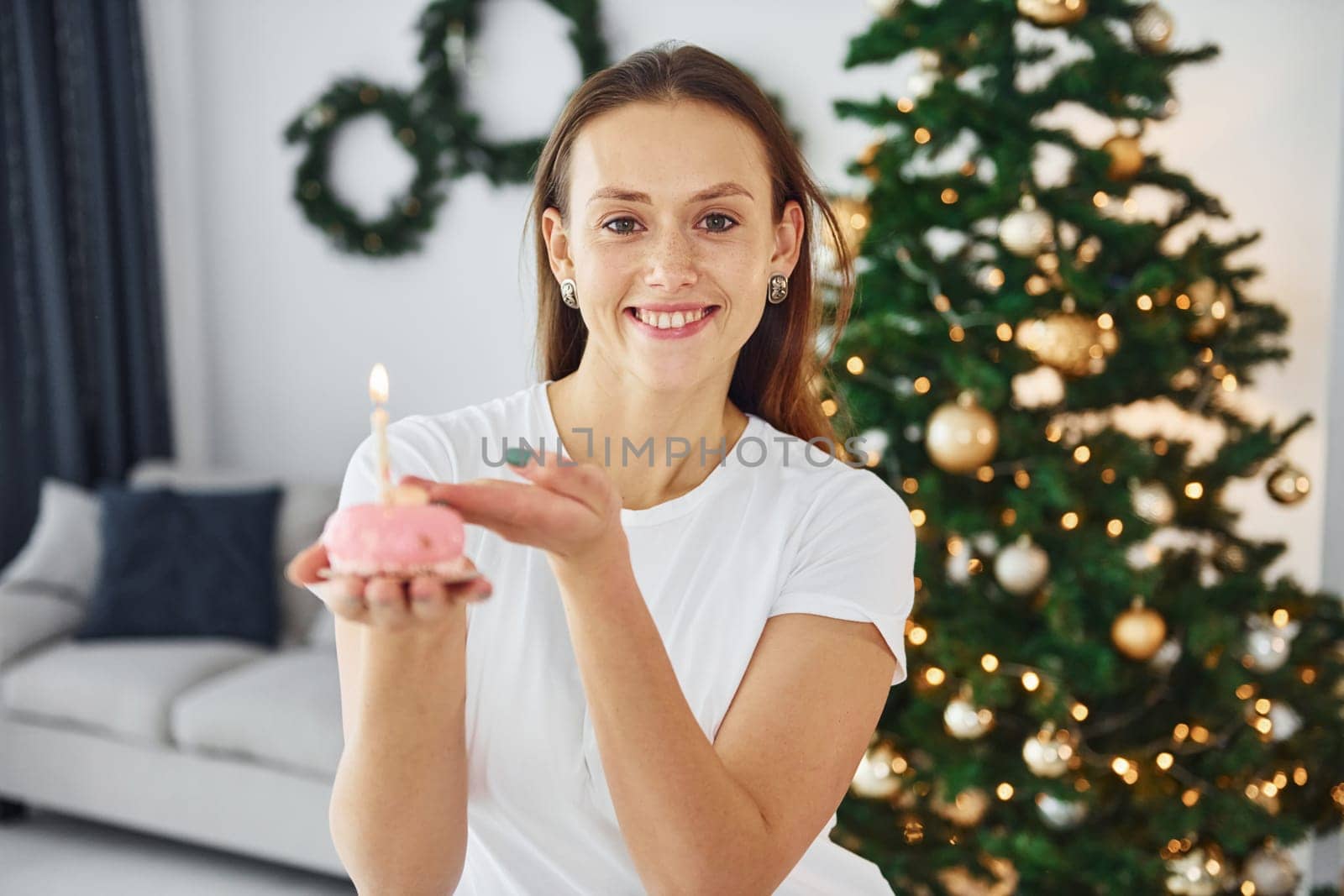 Christmas mood. Young woman in casual clothes is indoors in domestic room.