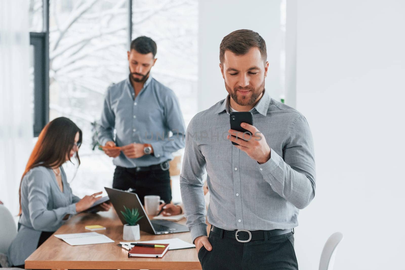 Man with phone. Group of business people that working on the project in the office.