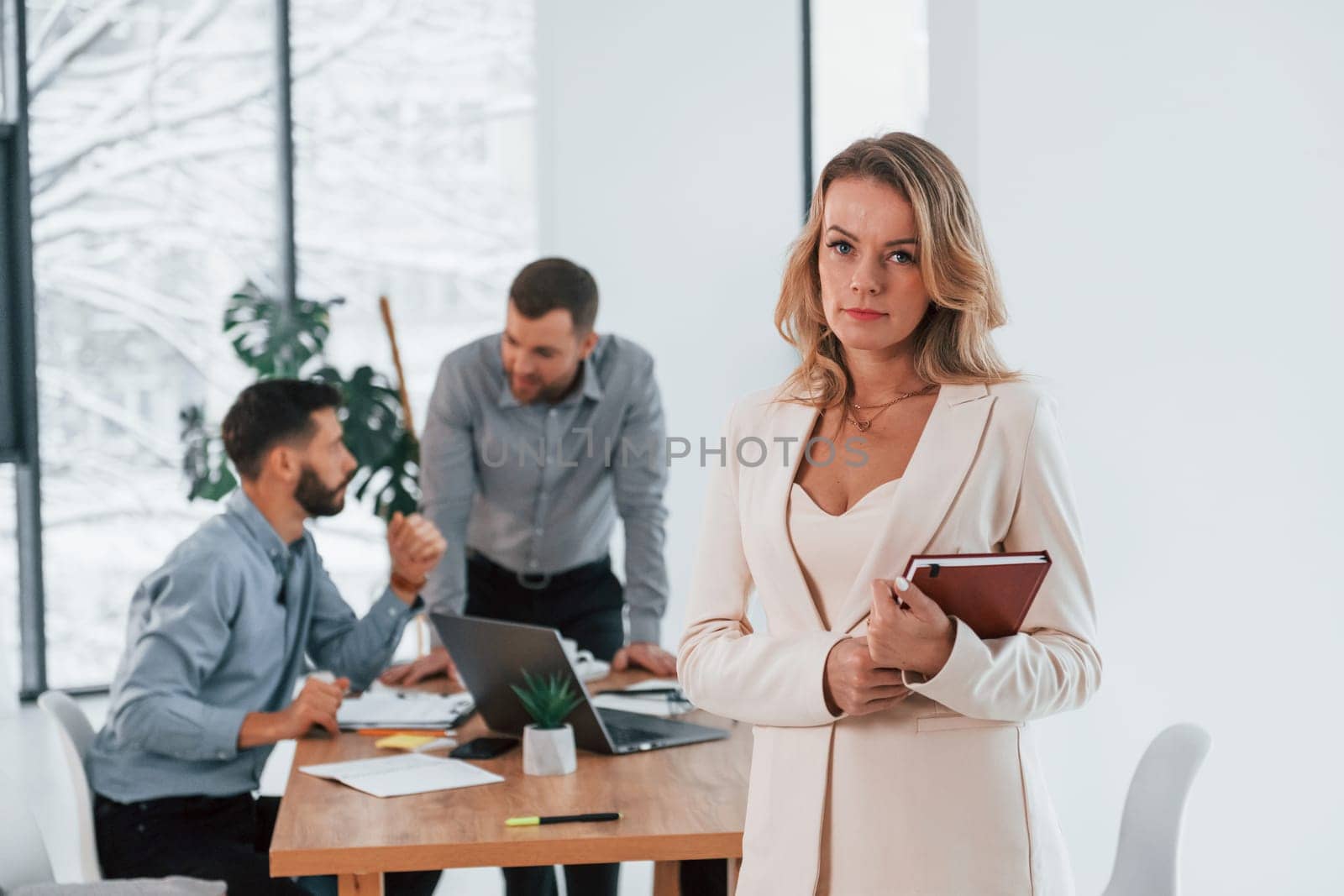 Woman in white clothes standing in front of her employees. Group of business people that working on the project in the office.