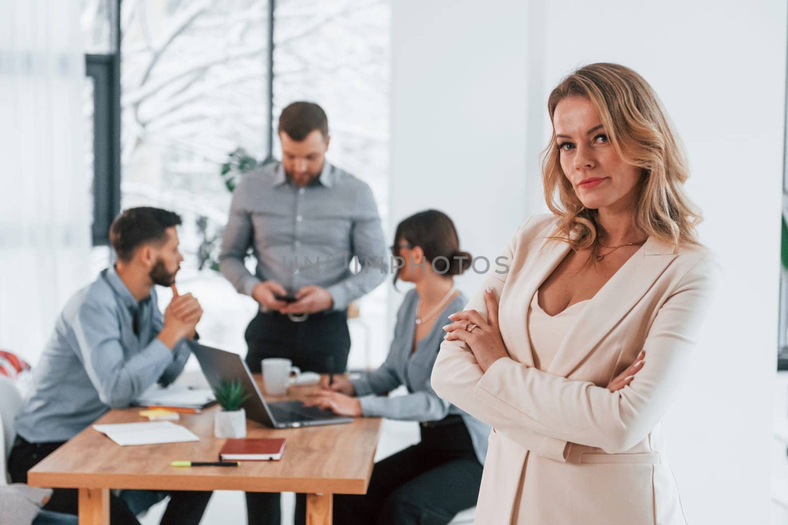 Woman in white clothes standing in front of her employees. Group of business people that working on the project in the office.