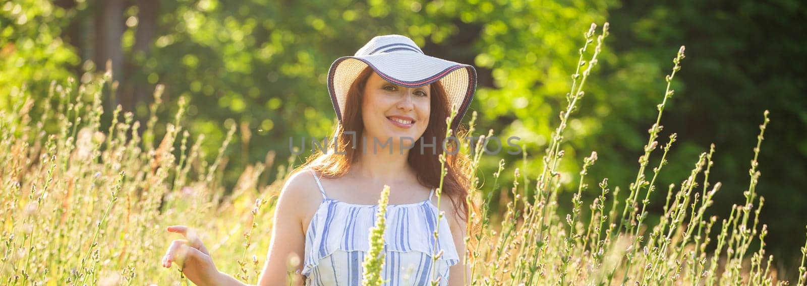 Banner woman walking among wildflowers on sunny summer day copy space. Concept of the joy of communicating with summer nature by Satura86