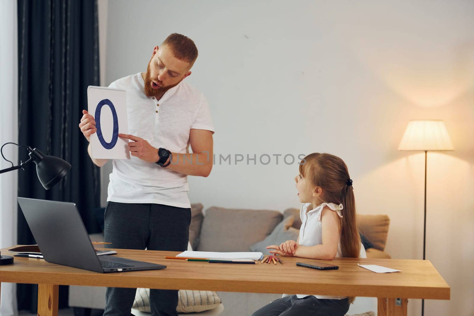 Learning letters. Father with his little daughter is at home together.