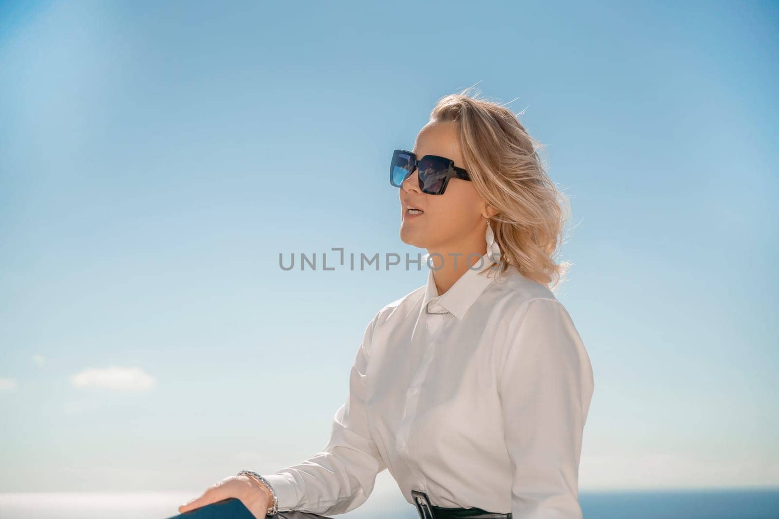 Freelance women sea working on a computer. Pretty middle aged woman with computer and phone outdoors with beautiful sea view. The concept of remote work