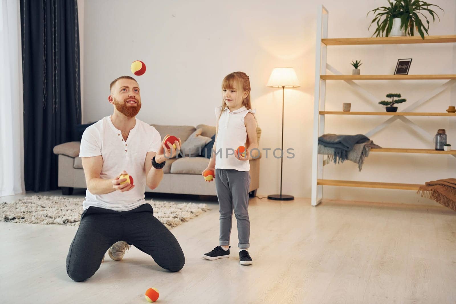 With throwing balls. Father with his little daughter is at home together.