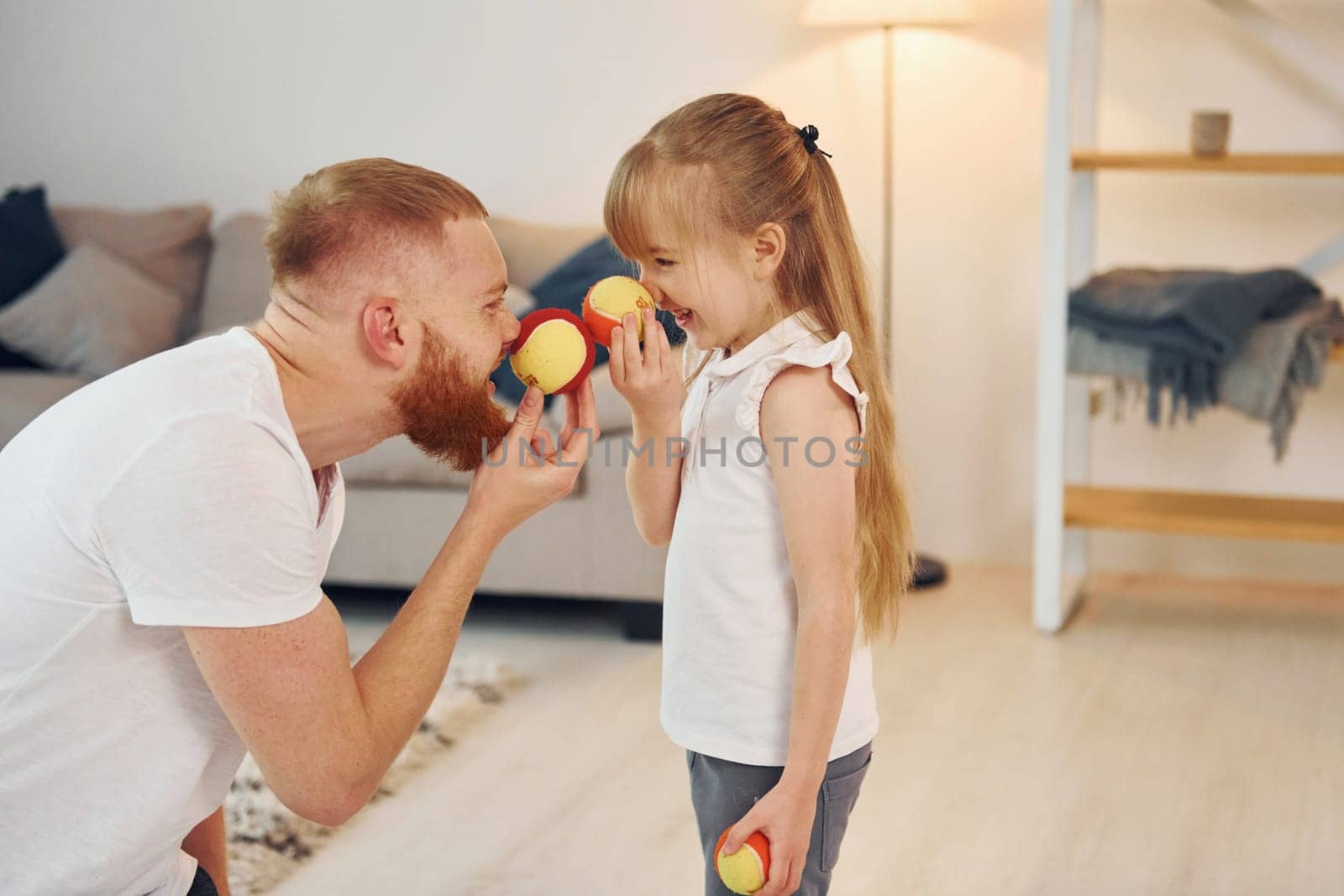 Holding balls. Father with his little daughter is at home together.