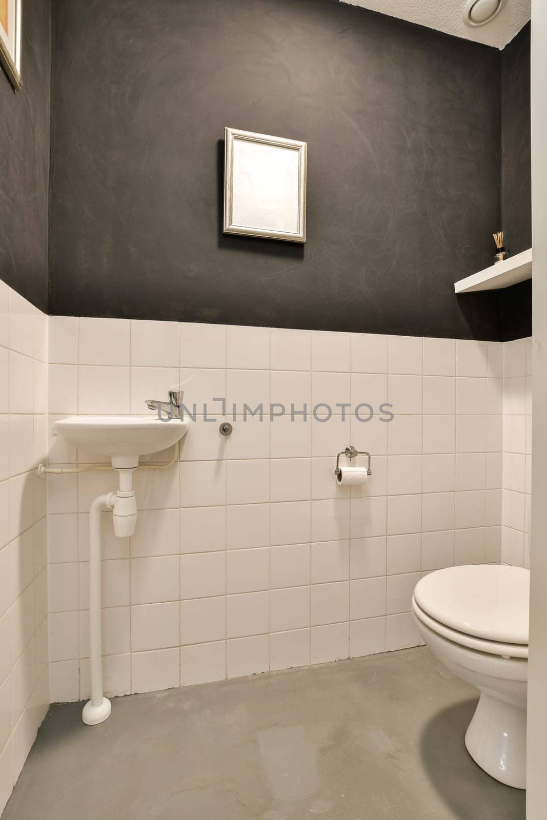 a bathroom with black walls and white tiles on the wall, there is a toilet in the corner next to the sink