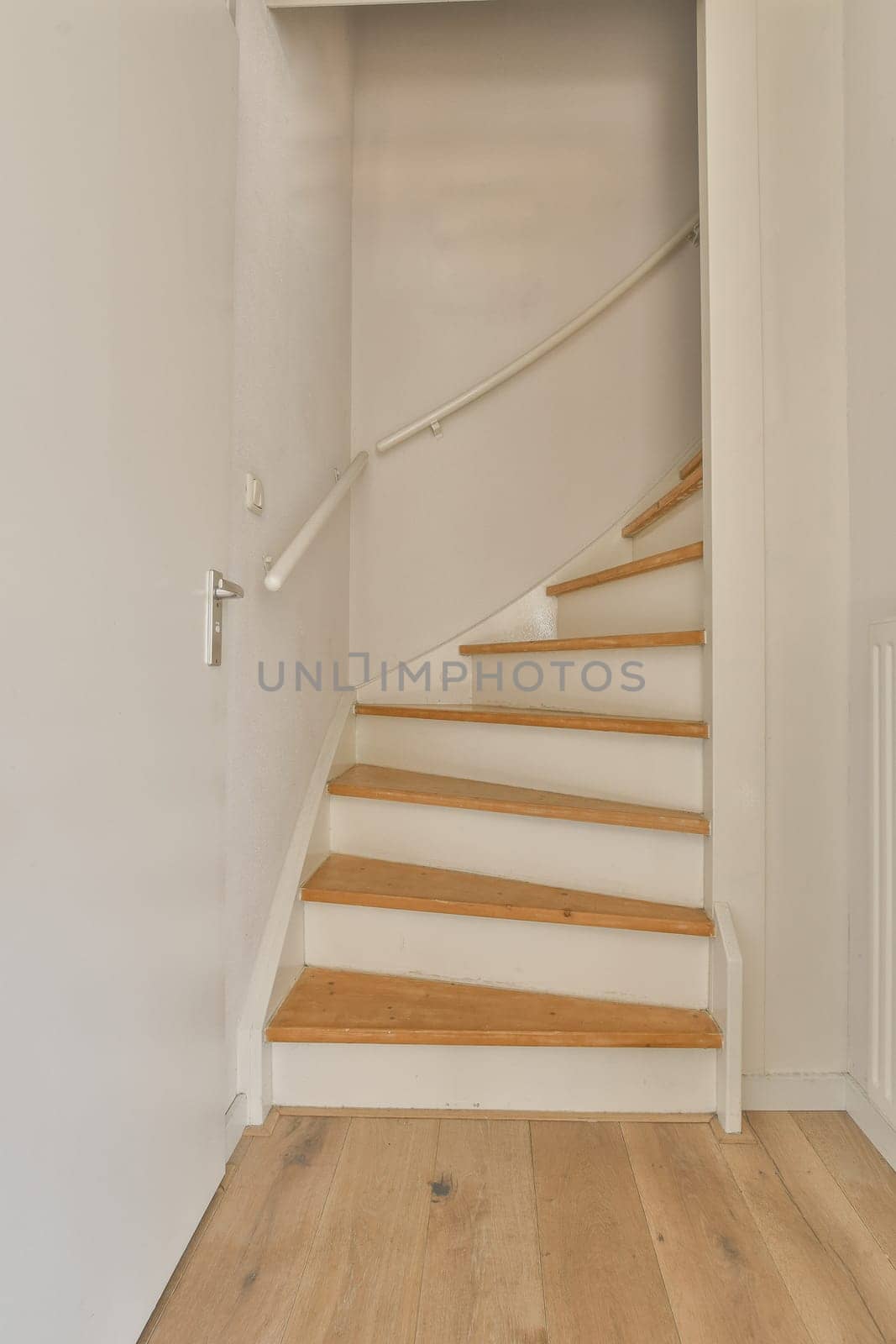 an empty room with stairs and wood flooring in the corner, looking towards the entrance to the living room
