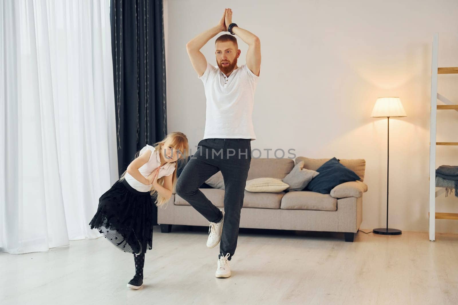 Teaching how to dance. Father with his little daughter is at home together.