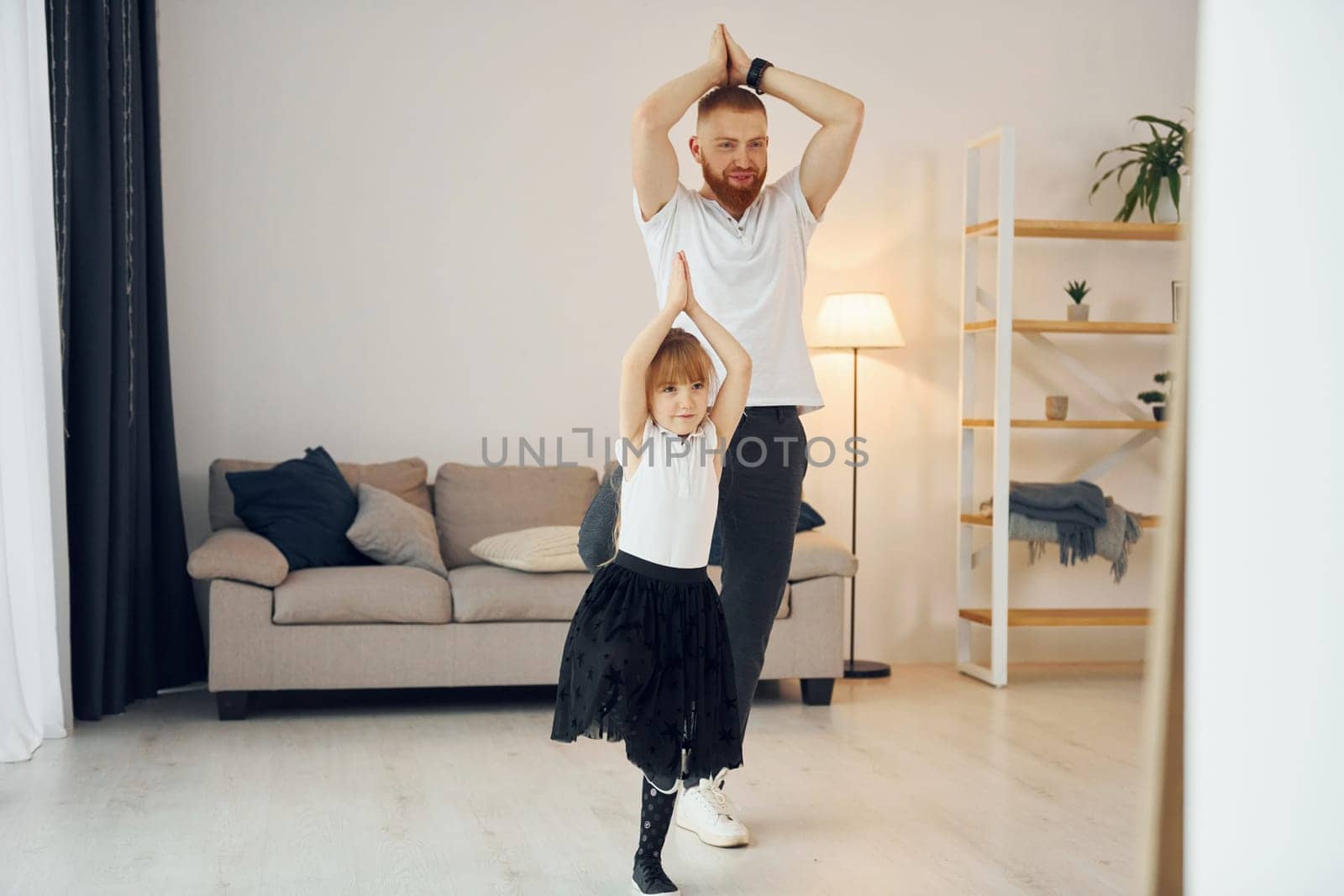Teaching how to dance. Father with his little daughter is at home together.