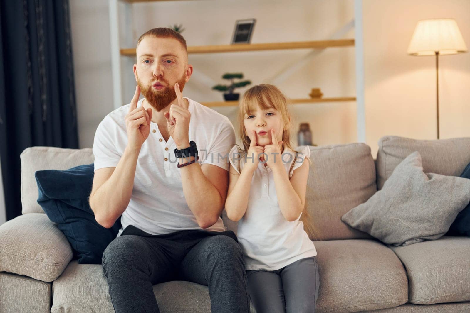 Learning to talk some words. Father with his little daughter is at home together.