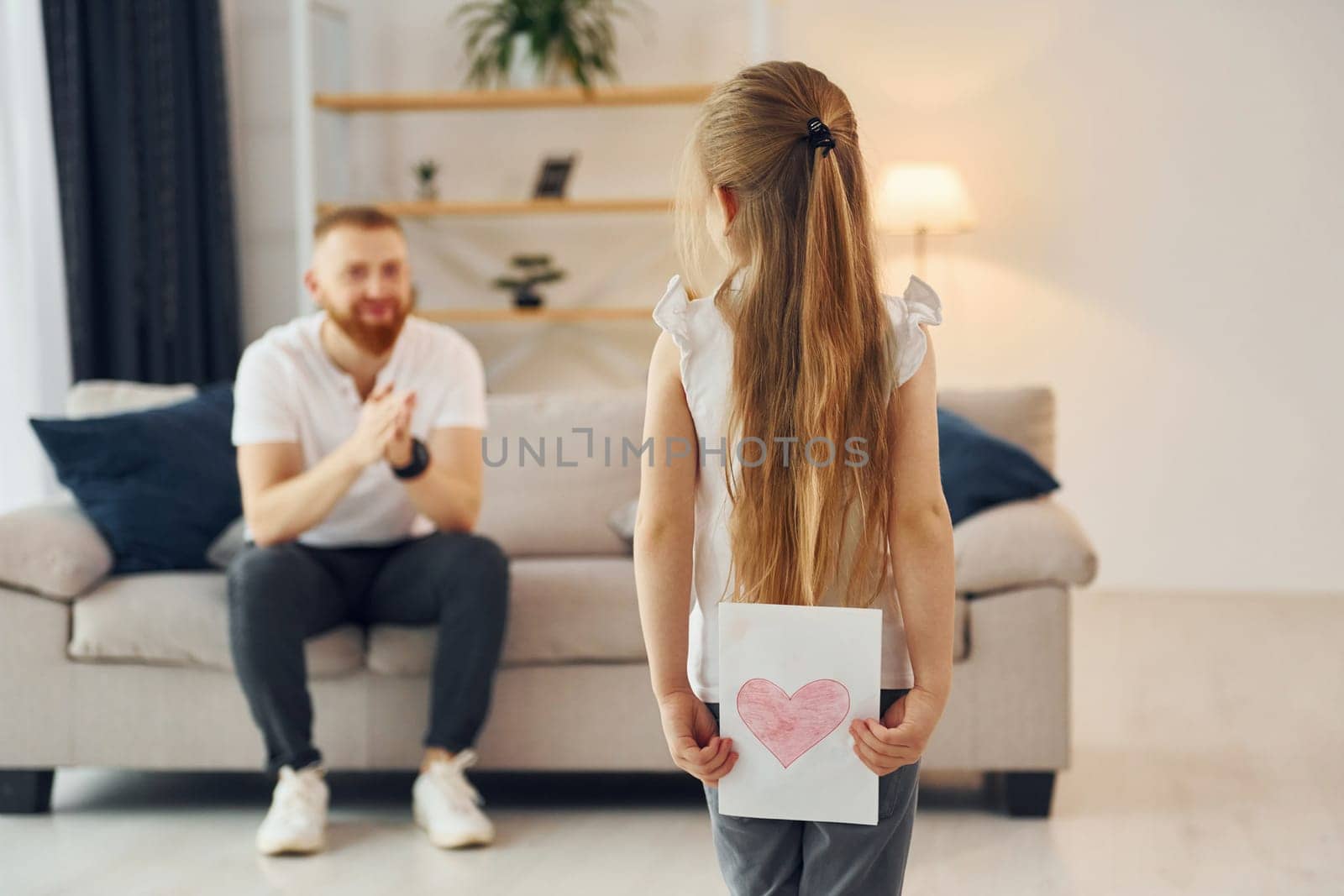 Little girl have gift for man. Father with his little daughter is at home together.