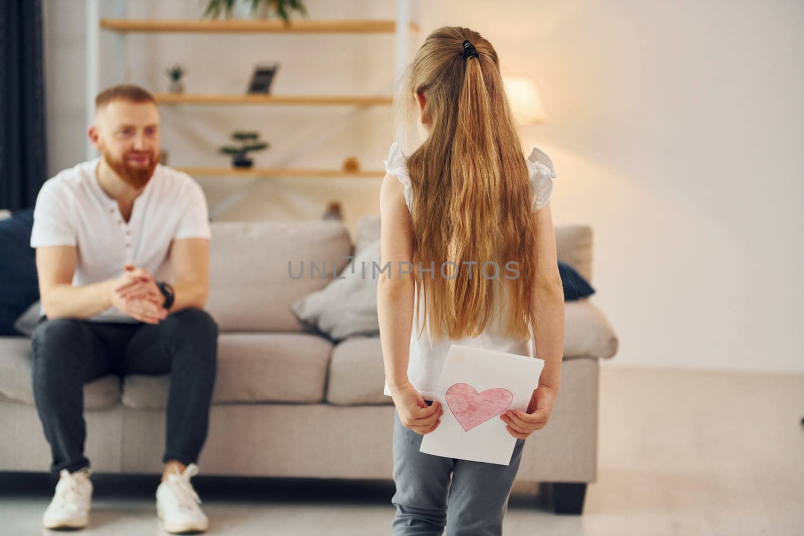 Little girl have gift for man. Father with his little daughter is at home together.