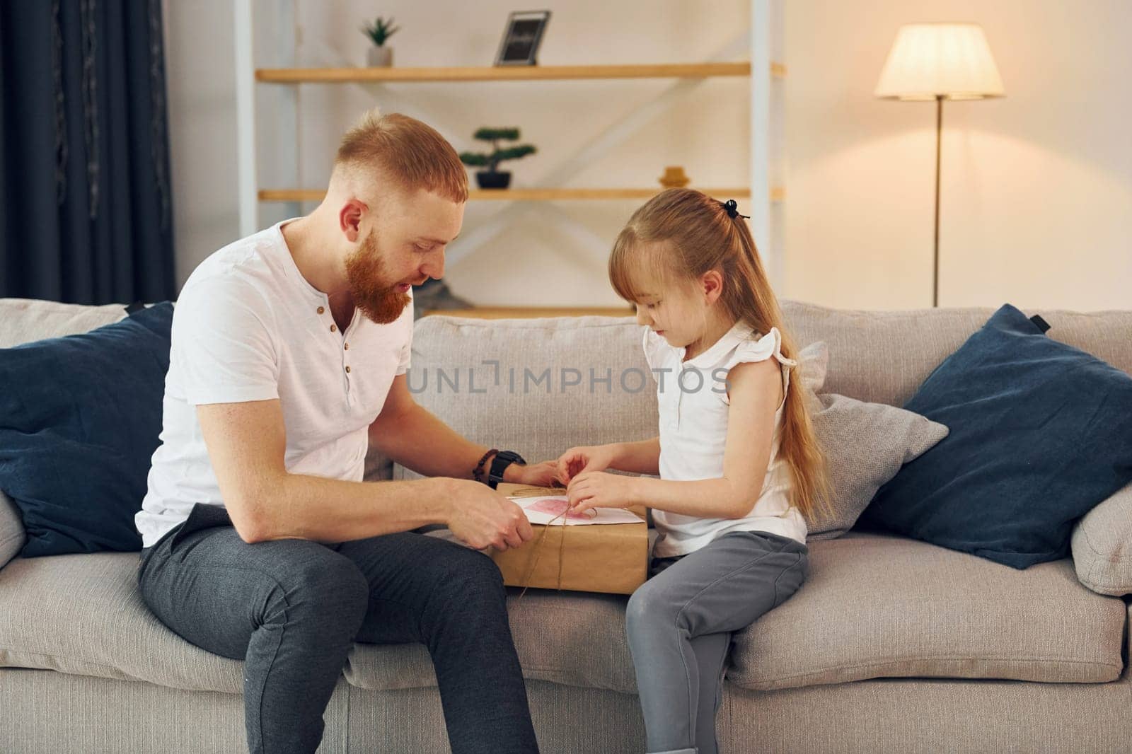 With gift box. Father with his little daughter is at home together.
