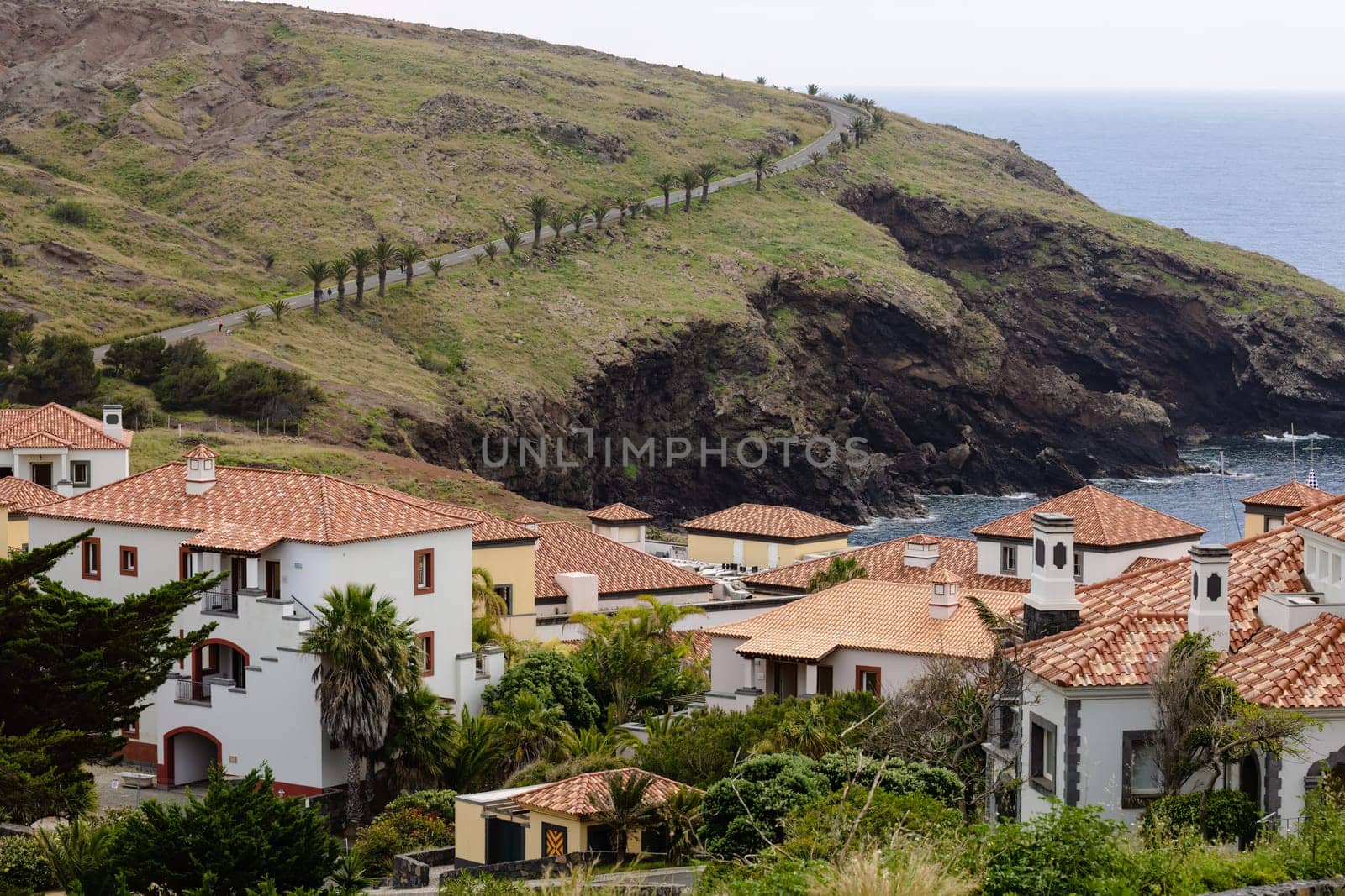 A rural village perched atop a hill, with picturesque architecture and lush trees surrounded by winding roads. Madeira, Portugal