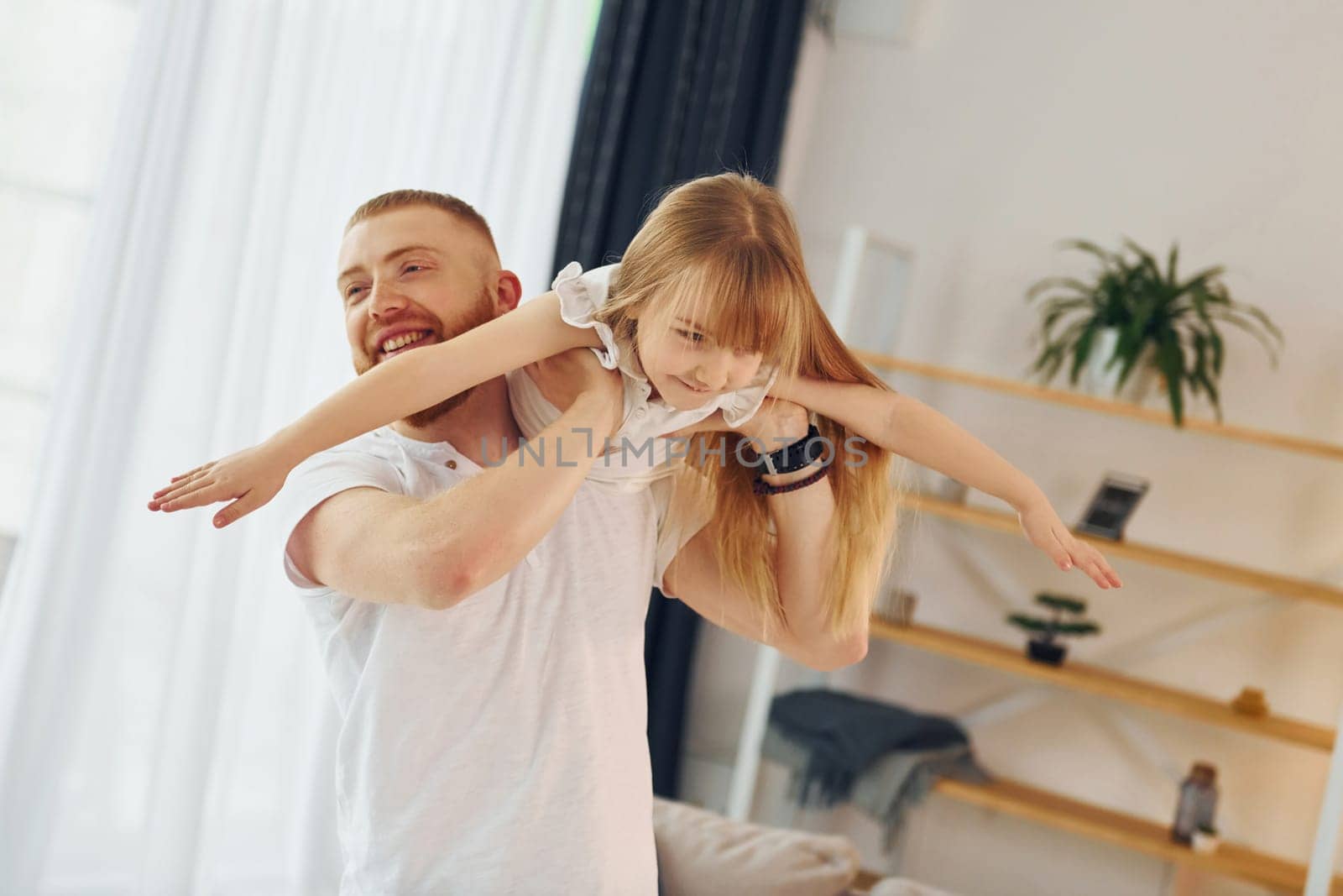 Man holding girl in hands. Father with his little daughter is at home together.