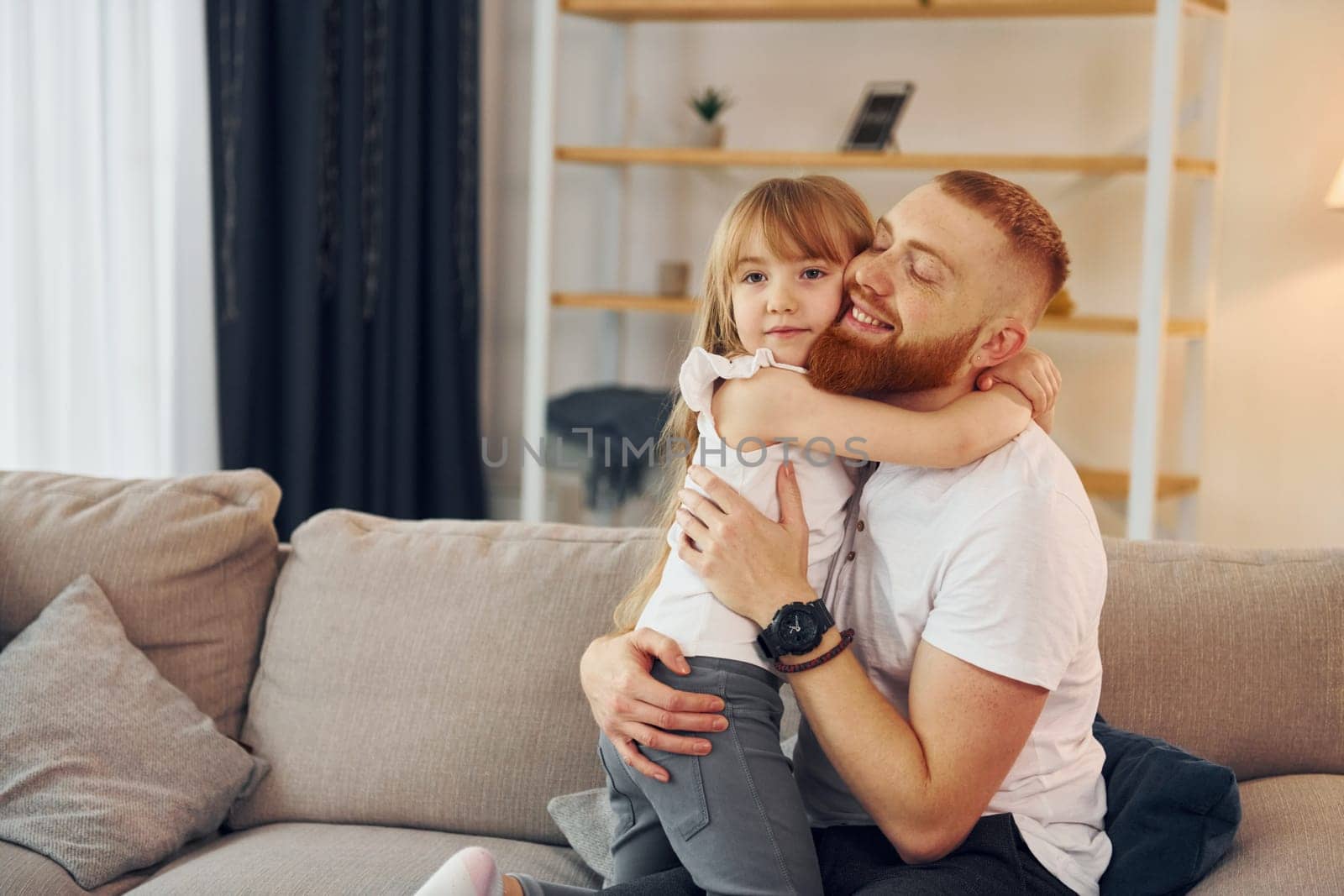 Embracing each other. Father with his little daughter is at home together.